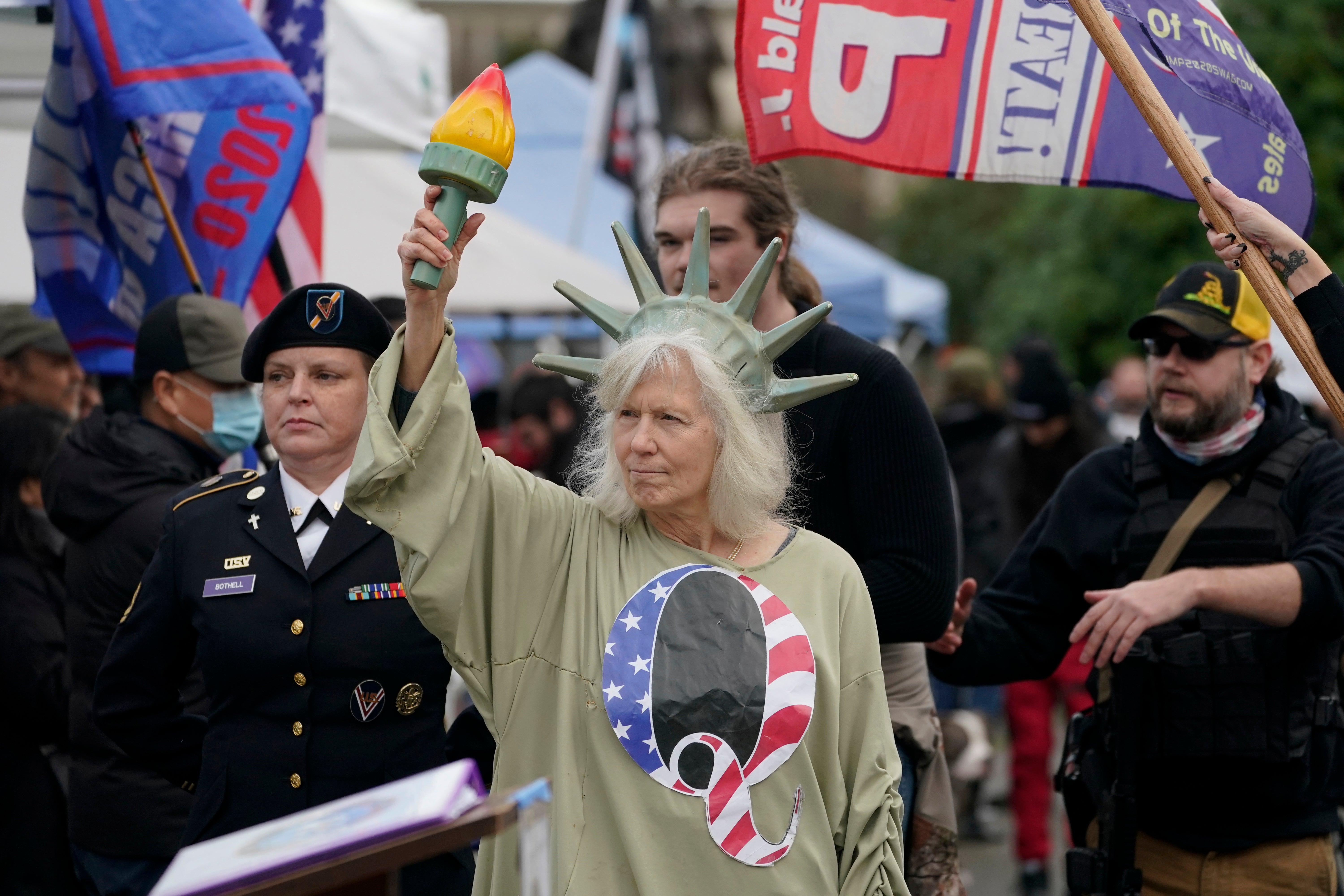 A person dressed as Lady Liberty wears a shirt with the letter Q, referring to QAnon, as protesters take part in a protest, Wednesday, Jan. 6, 2021