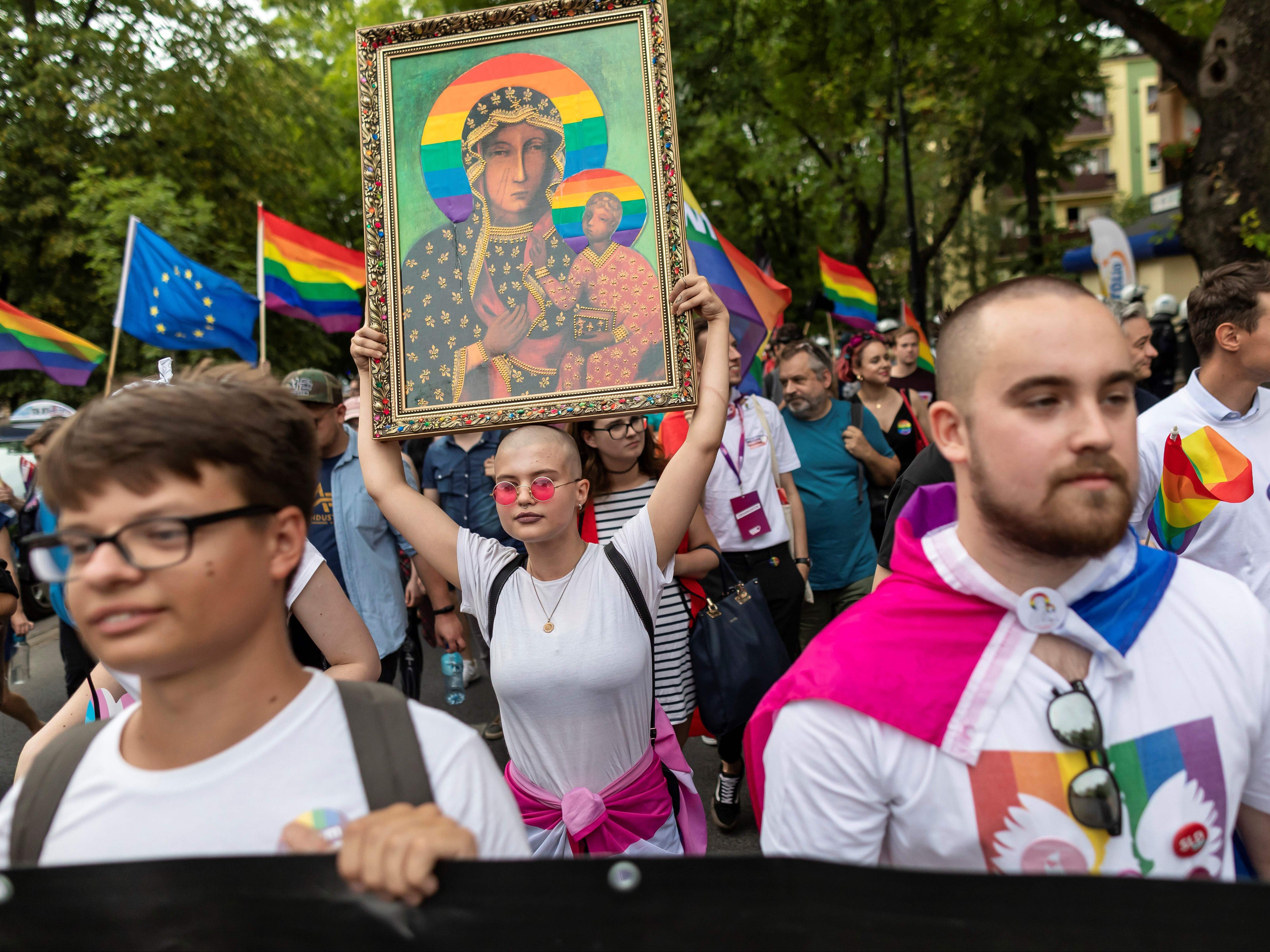 A woman holds a frame depicting the Virgin Mary with a rainbow halo during the first gay pride organised in Plock, central Poland, in 2019