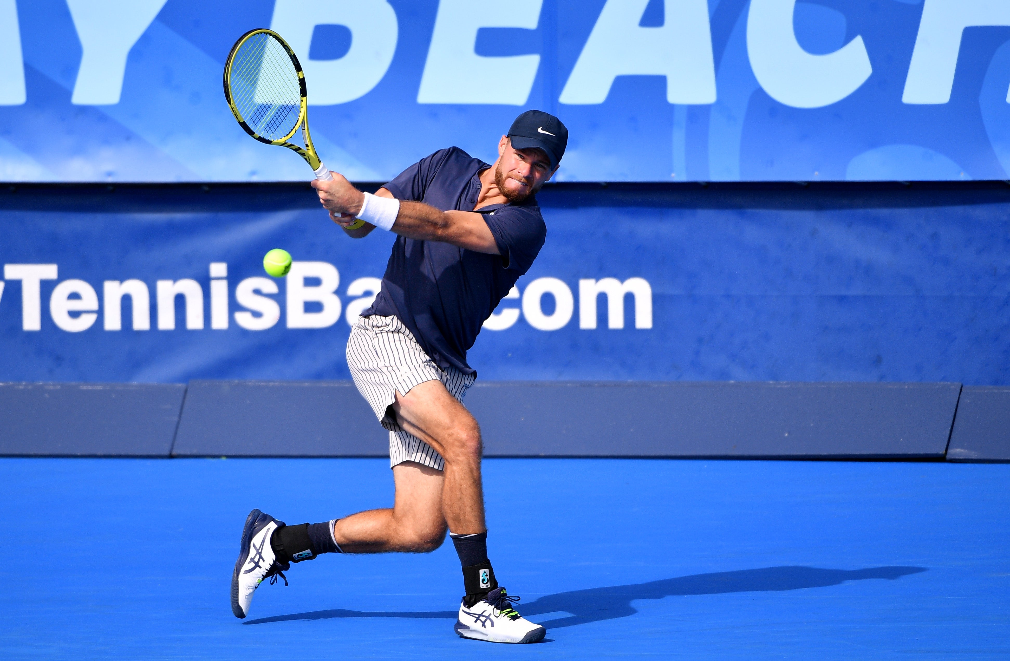 Christian Harrison of USA returns a backhand against Gianluca Mager