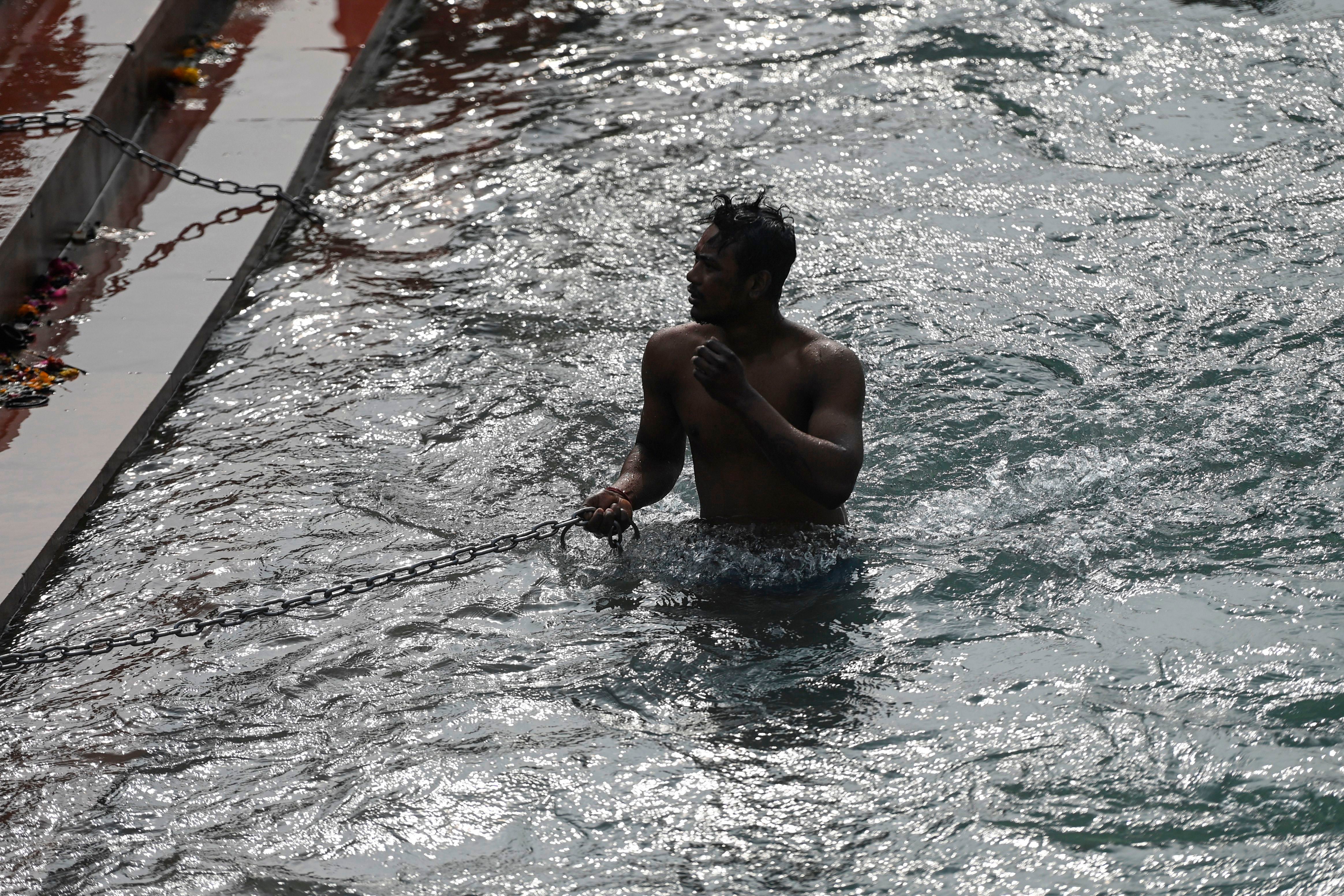 A Hindu devotee takes a holy dip in the waters of the River Ganges during Makar Sankranti, a day considered to be of great religious significance in the Hindu mythology, on the first day of the religious Kumbh Mela festival in Haridwar on 14 January 2021