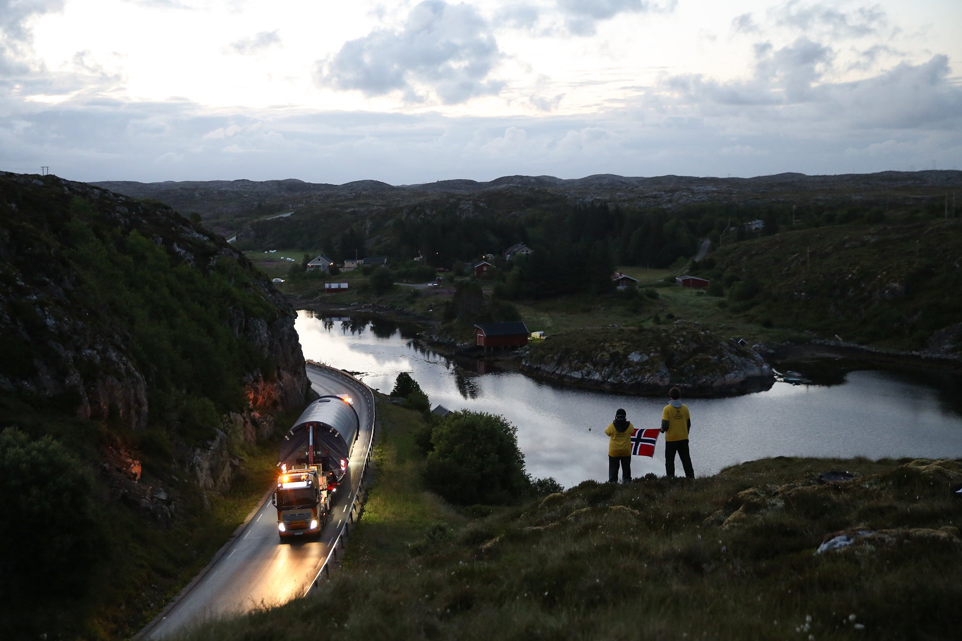 Protesters holding a Norwegian flag as parts of a turbine arrive on the island of Frøya on the Norwegian coast