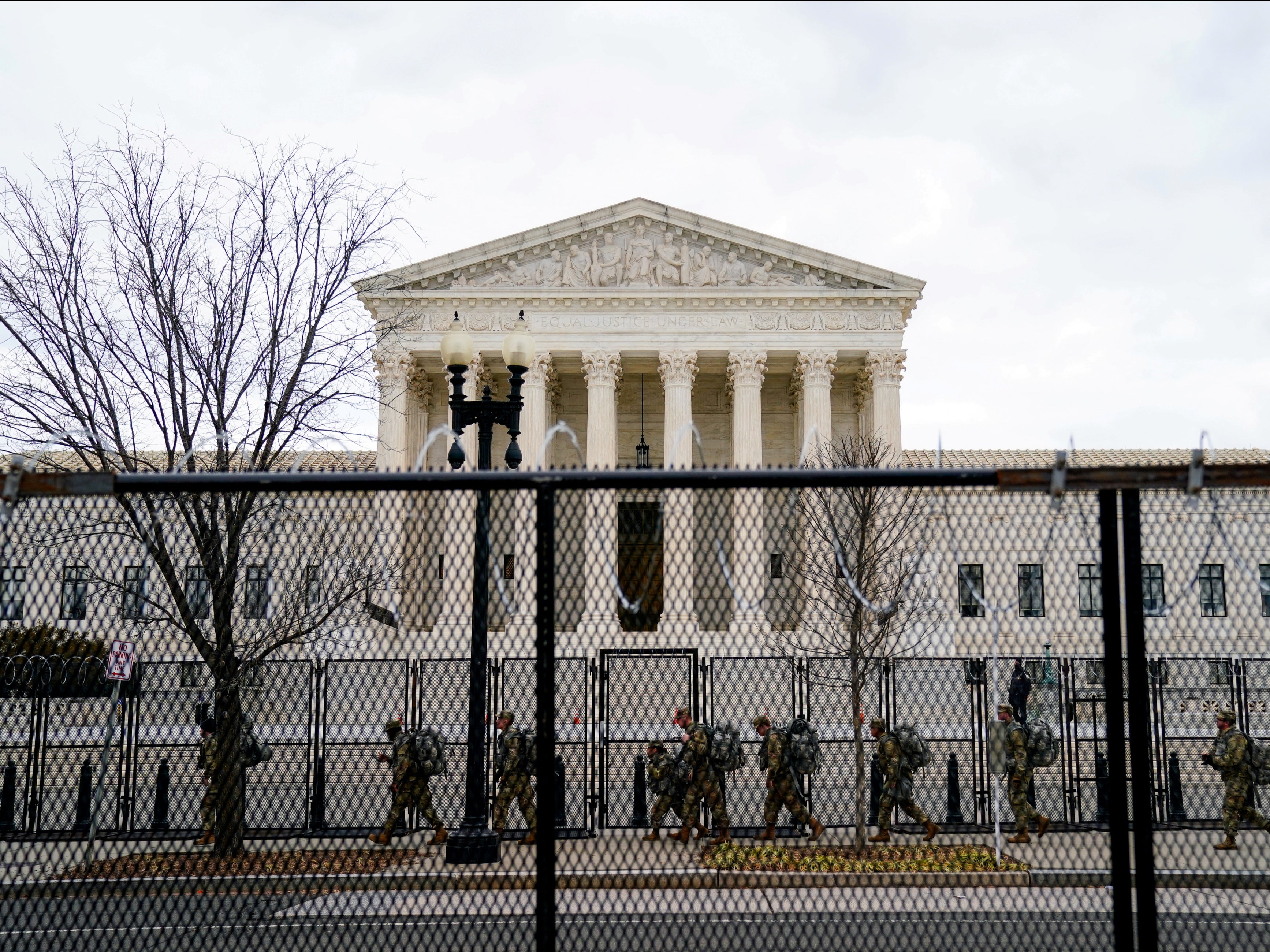 <p>National Guard troops walk behind fencing in front of the US Supreme Court as security tightens ahead of presidential inaugural events on Capitol Hill in Washington, DC</p>
