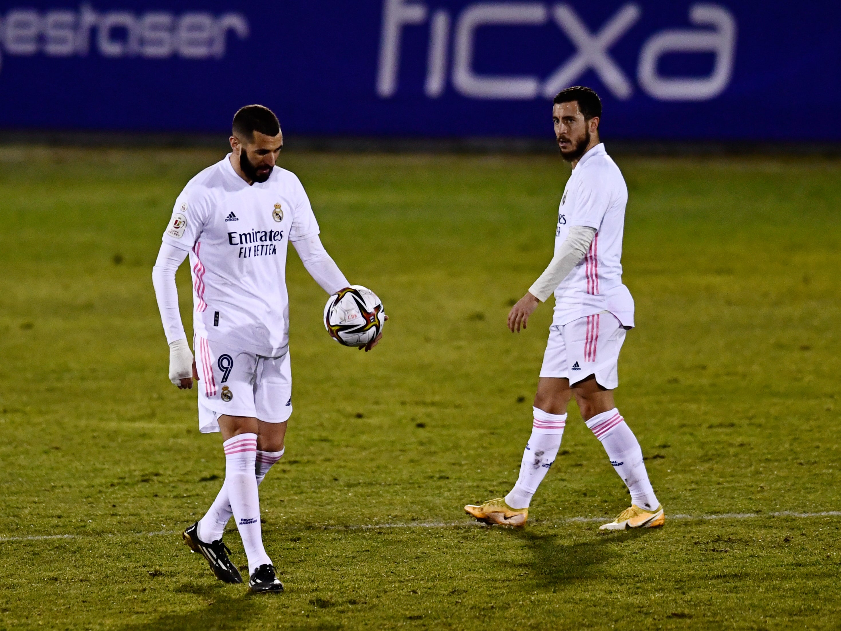 Karim Benzema walks with the ball watched by Eden Hazard