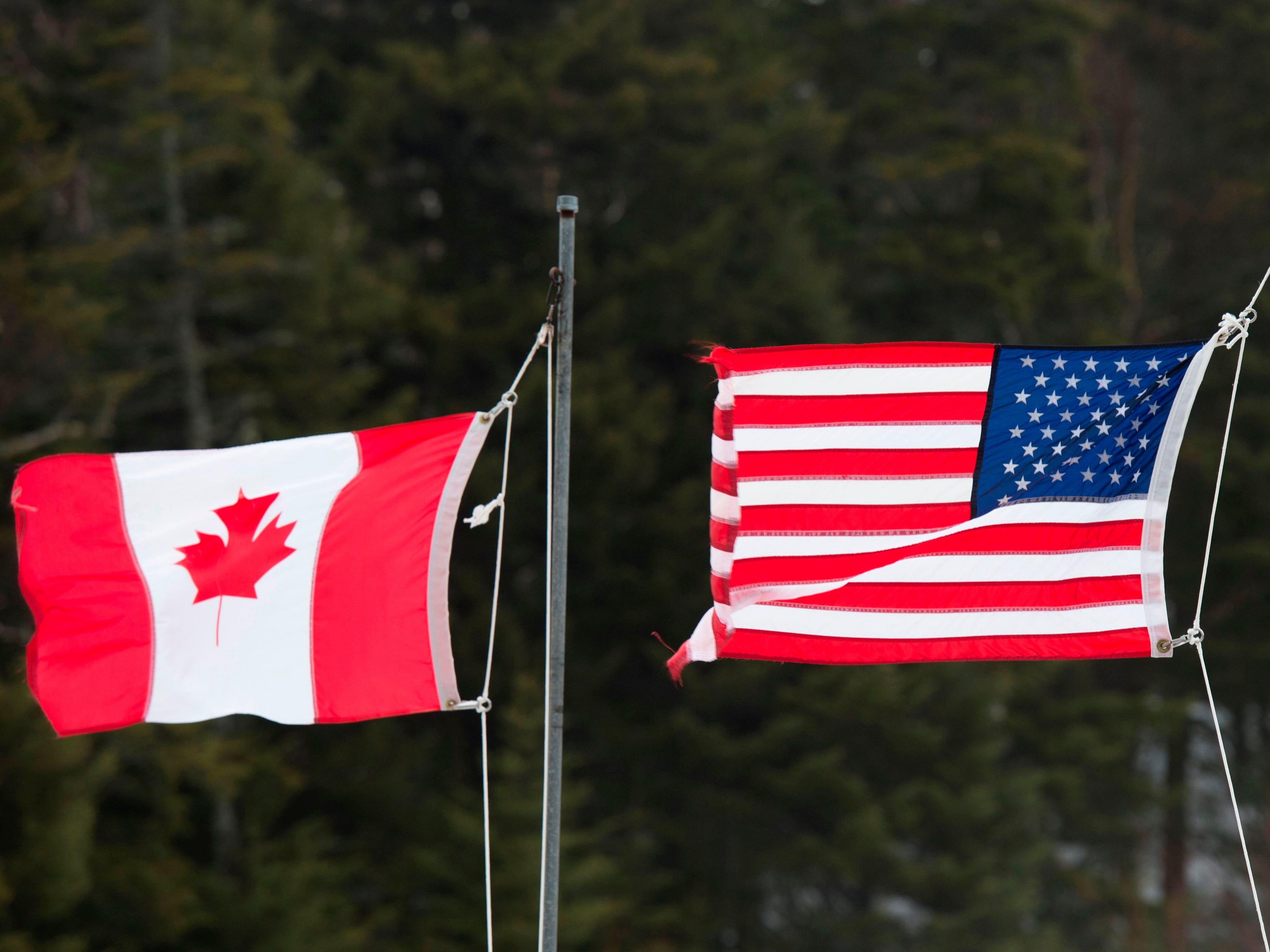 <p>Canadian and American flags are seen at the US/Canada border on 1 March 2017, in Pittsburg, New Hampshire</p>