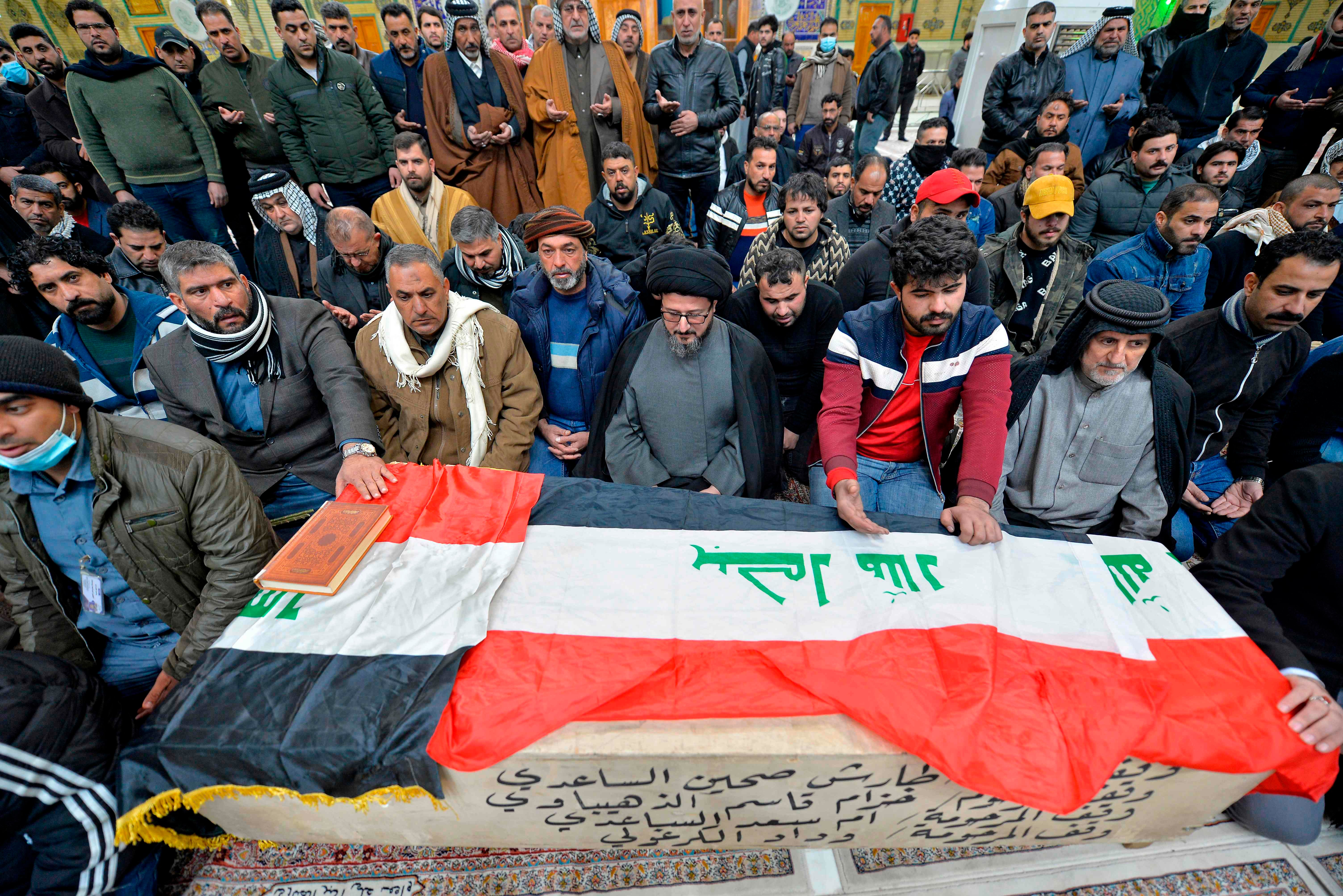 Iraqi mourners pray over the coffin of a victim who was killed in the bombings