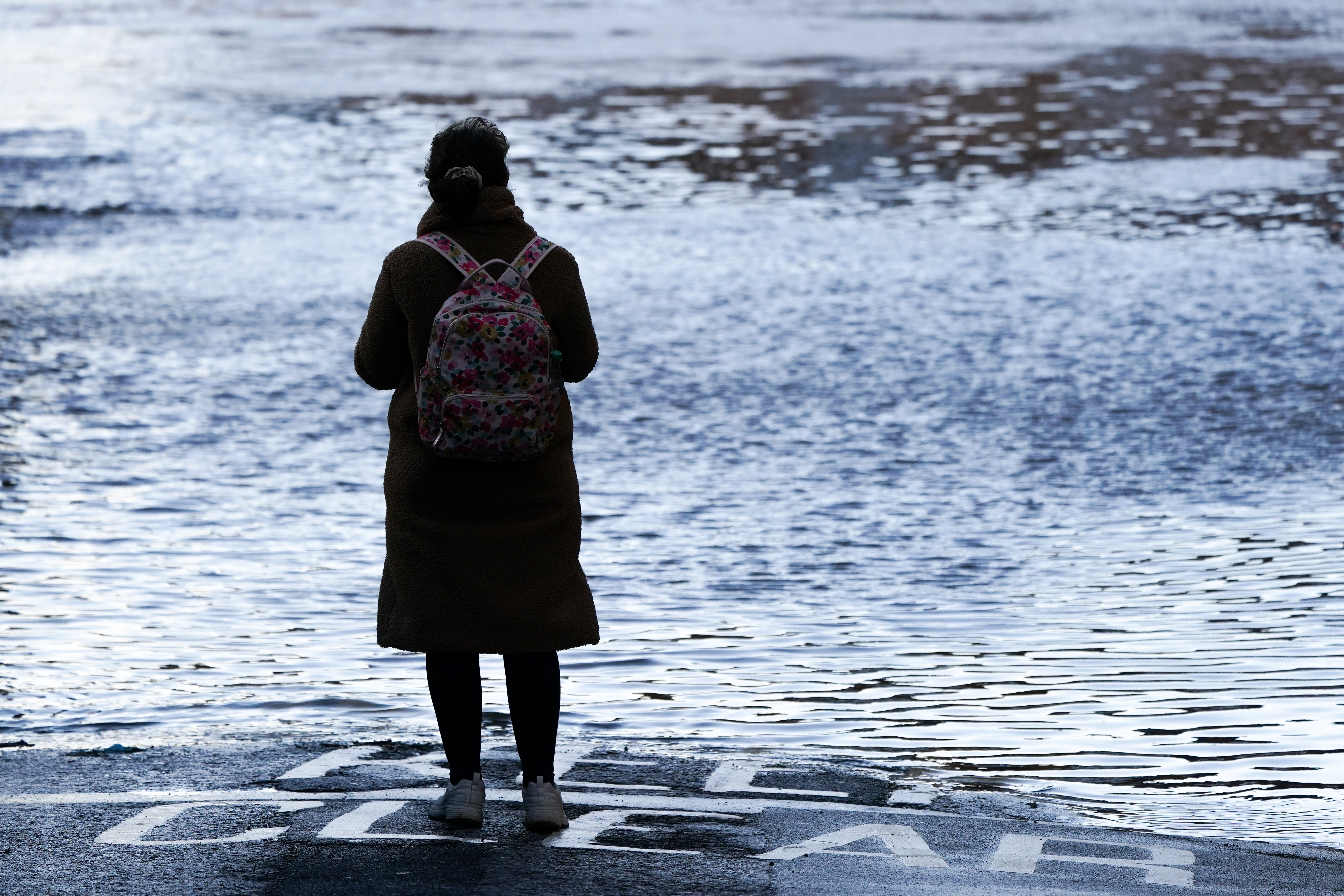 A woman looks out over the River Ouse in York as it floods following rain and melting snow on January 21, 2021 in York, England.