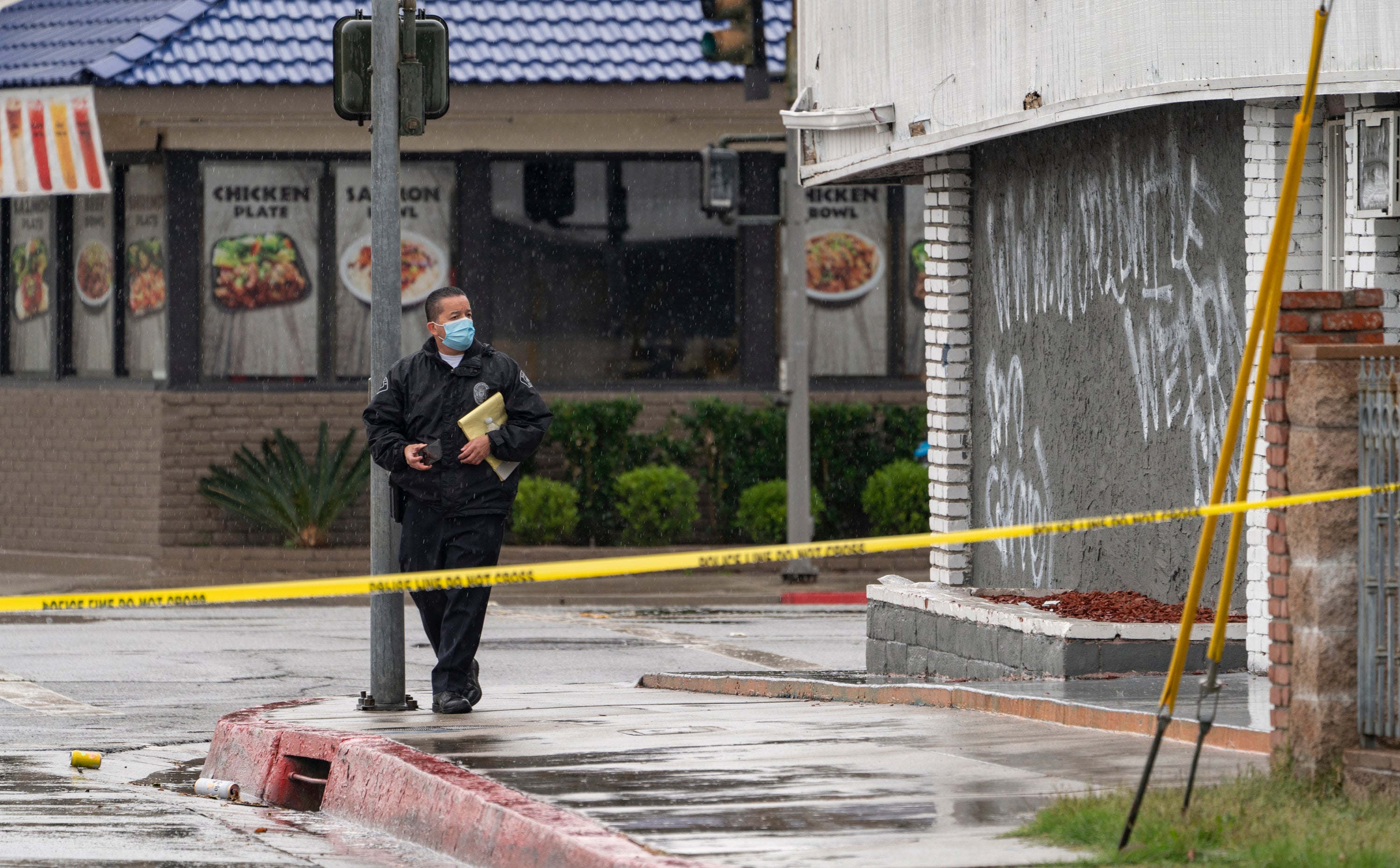 El Monte Police Chief David Reynoso, left, takes pictures of graffiti on the side wall of the First Works Baptist Church, after an explosion in El Monte, California on 23 January 2021.&nbsp;