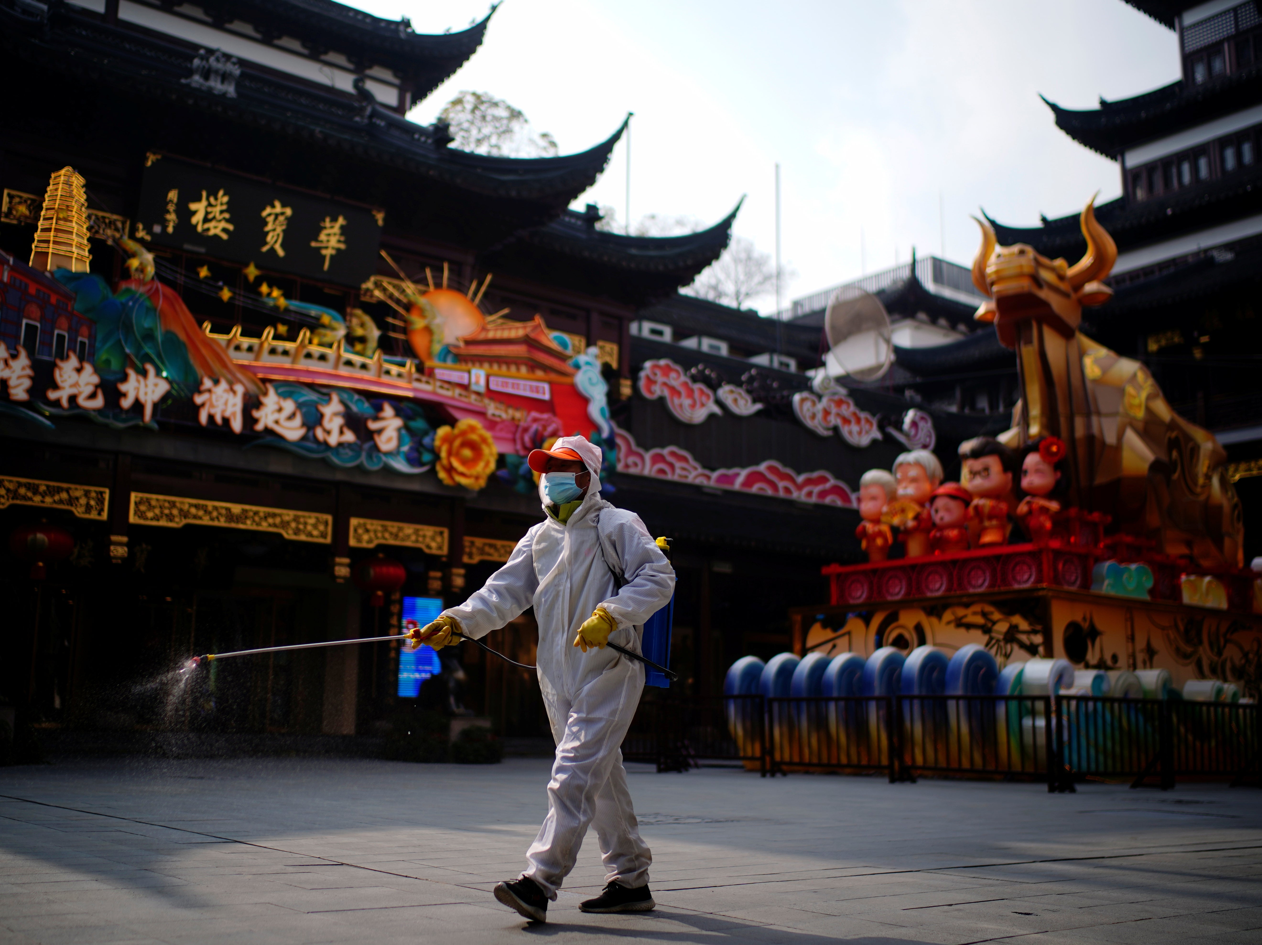 A worker disinfects Yuyuan, or Yu Garden, near an ox installation set up ahead of the Chinese Lunar New Year festivity, following the coronavirus disease (COVID-19) outbreak in Shanghai