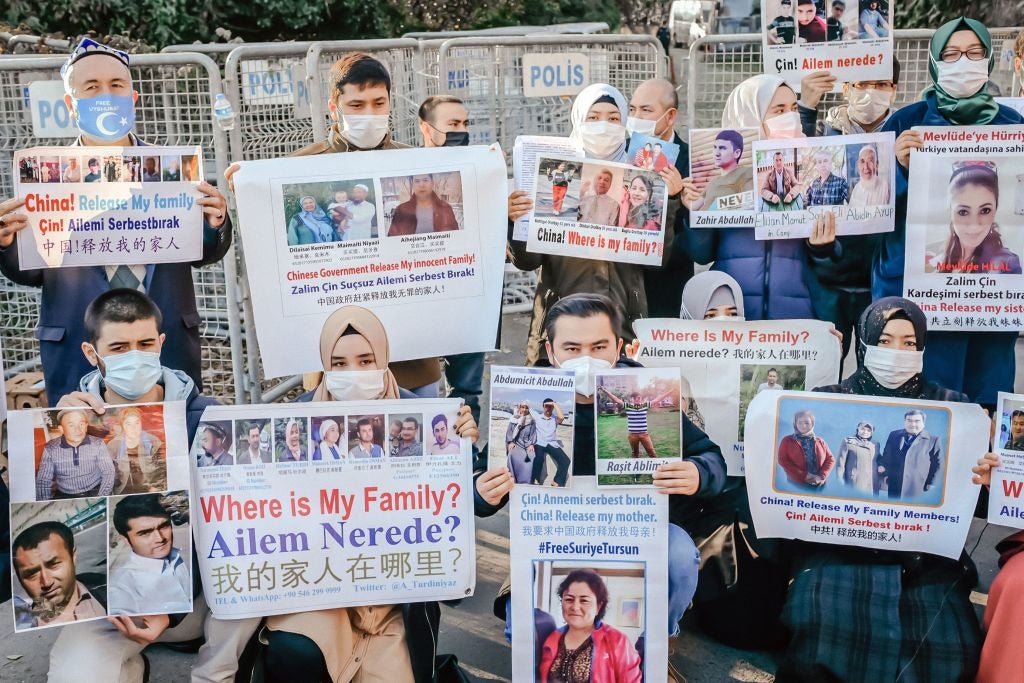 Members of the Muslim Uighur community hold placards as they demonstrate over the whereabouts of family members