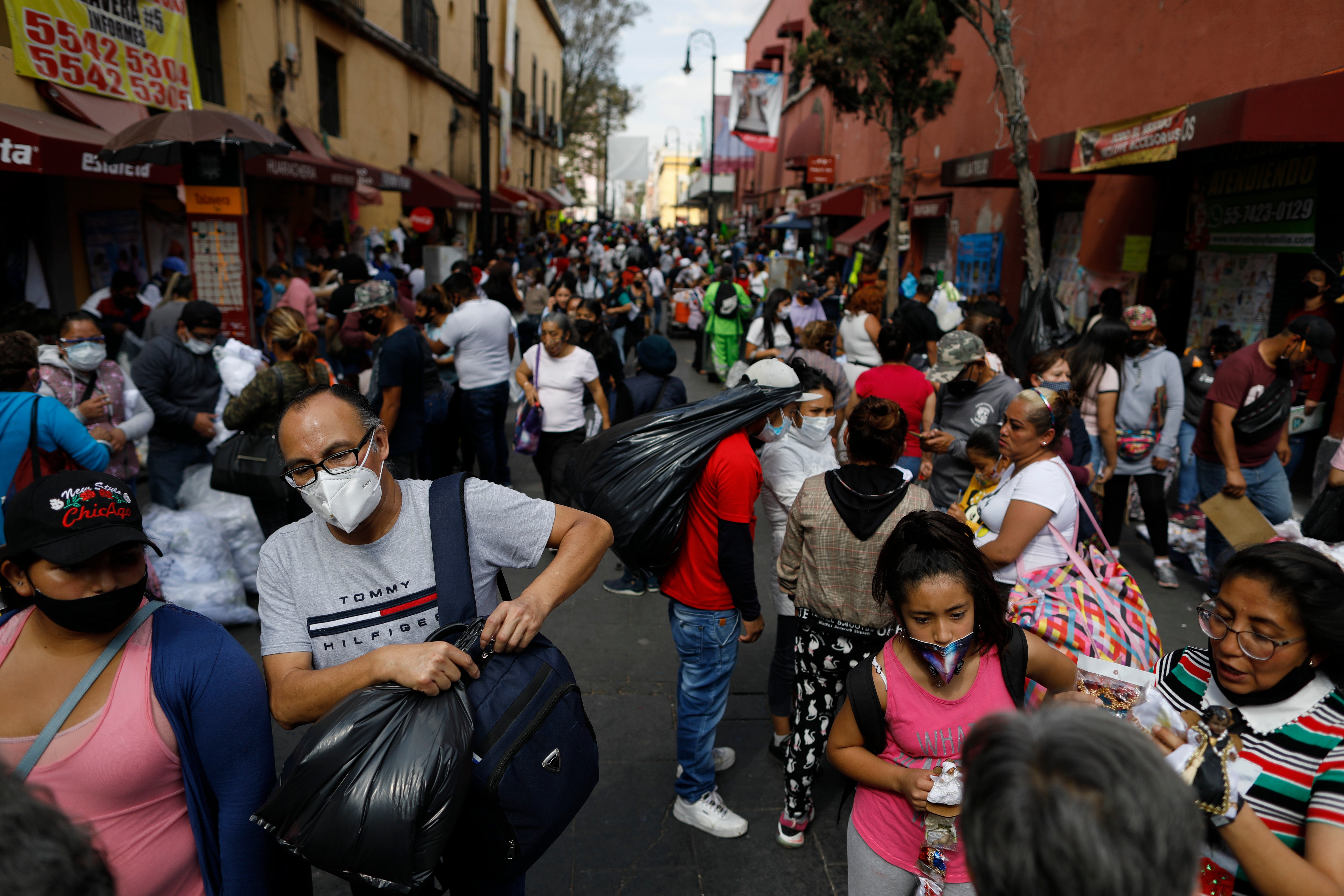 Shoppers and vendors mingle in a street for the sale of Baby Jesus figures and accessories, as Mexicans prepare to celebrate “Dia de la Candelaria” or Candlemas Day, amid a surge in the COVID-19 pandemic, in the center of Mexico City, Thursday, Jan. 28.