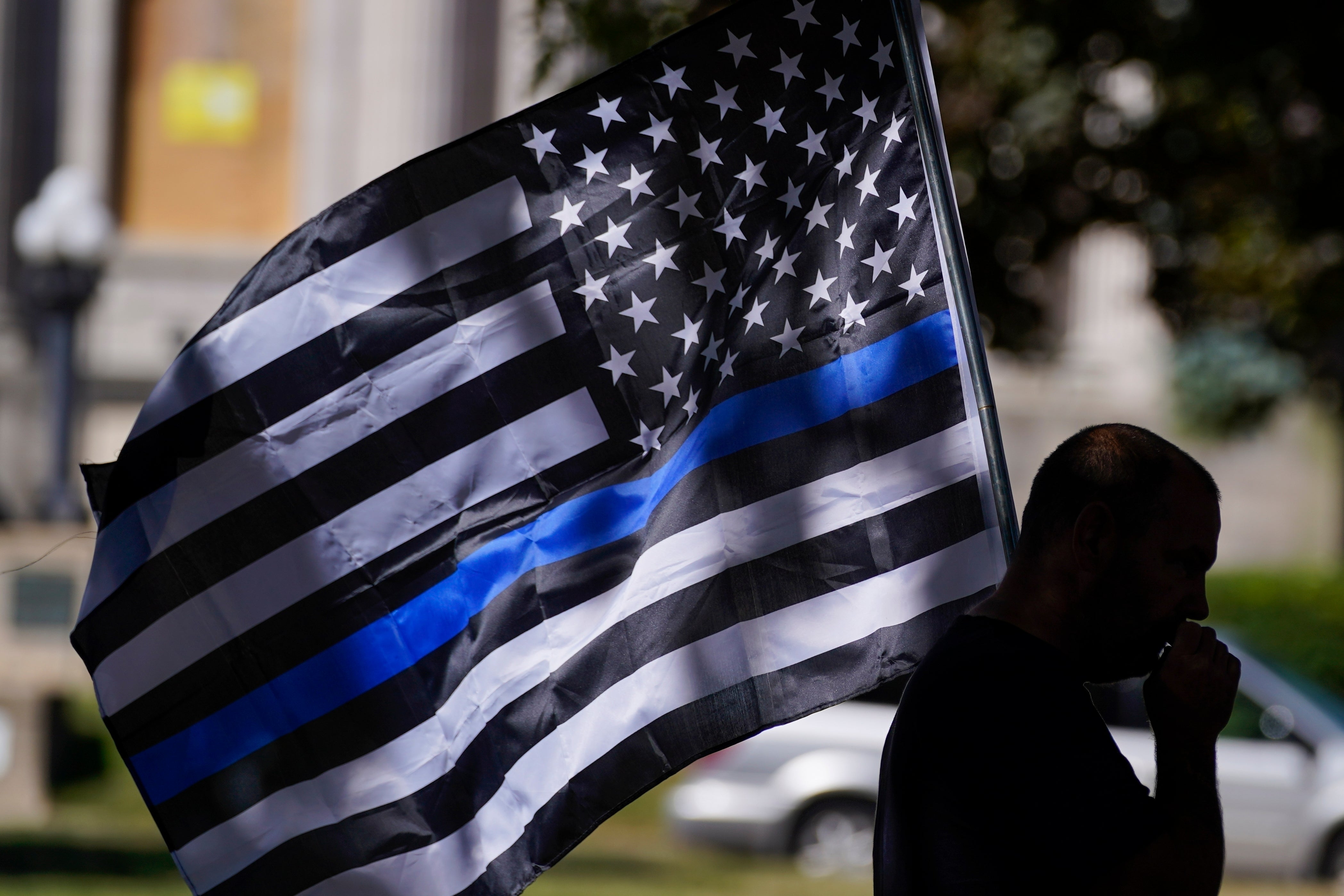 A man carries a ‘thin blue line’ flag at a Blue Lives Matter rally in Kenosha, Wisconsin, in 2020