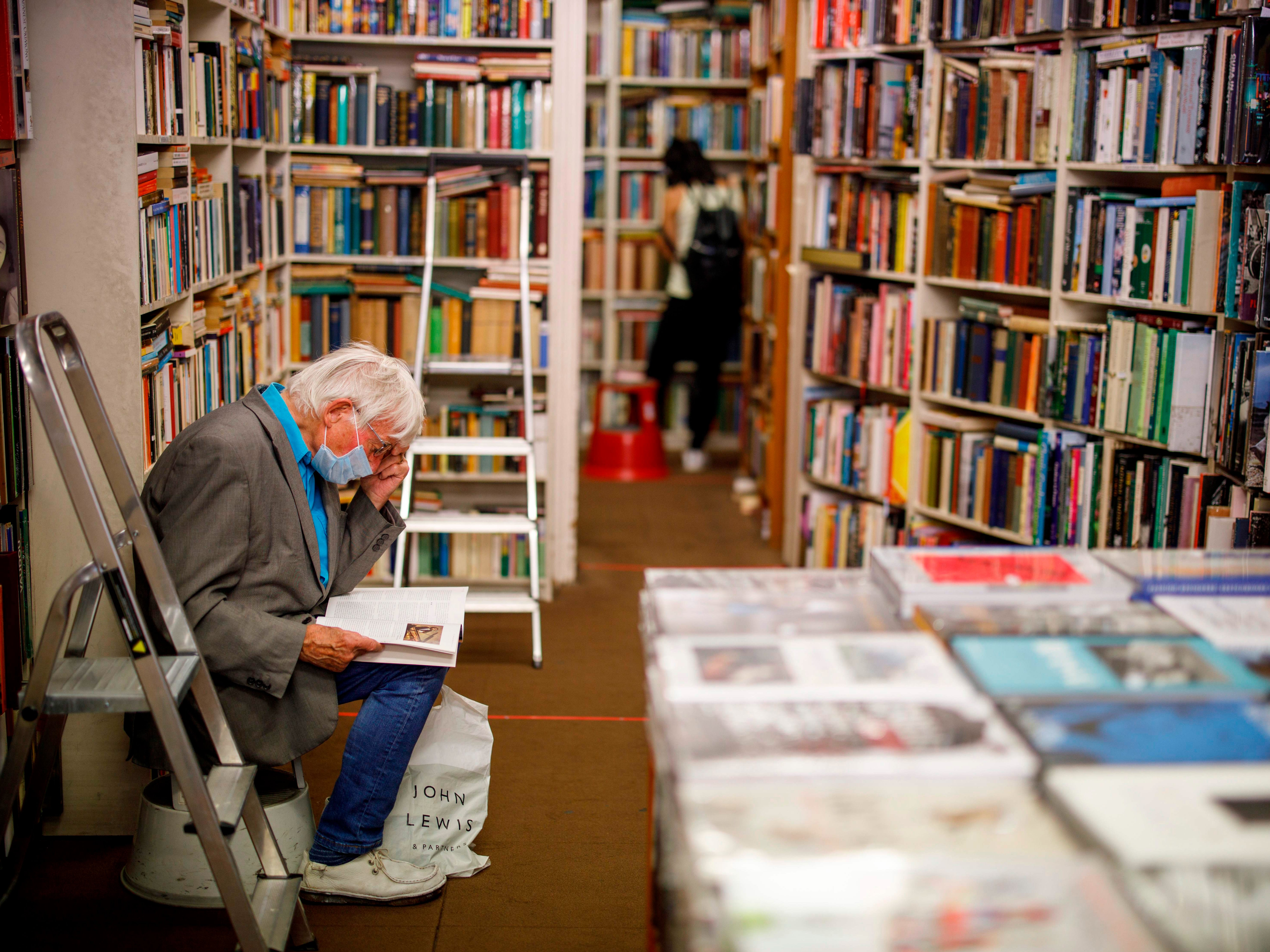 A man wearing a protective face mask browses books in Henry Pordes secondhand book shop in central London on 15 June 2020