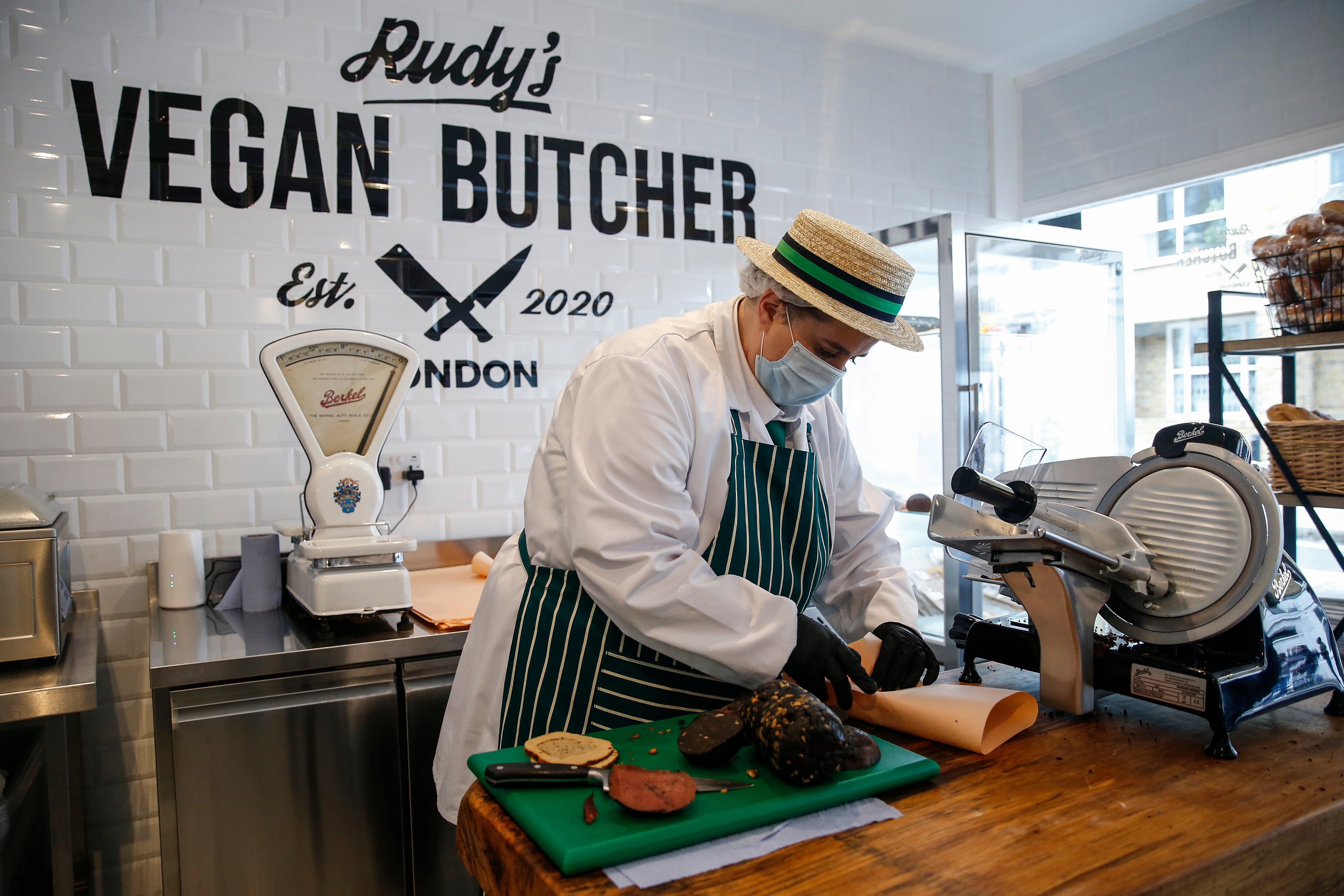 An employee slices meat alternatives at a vegan butcher in north London