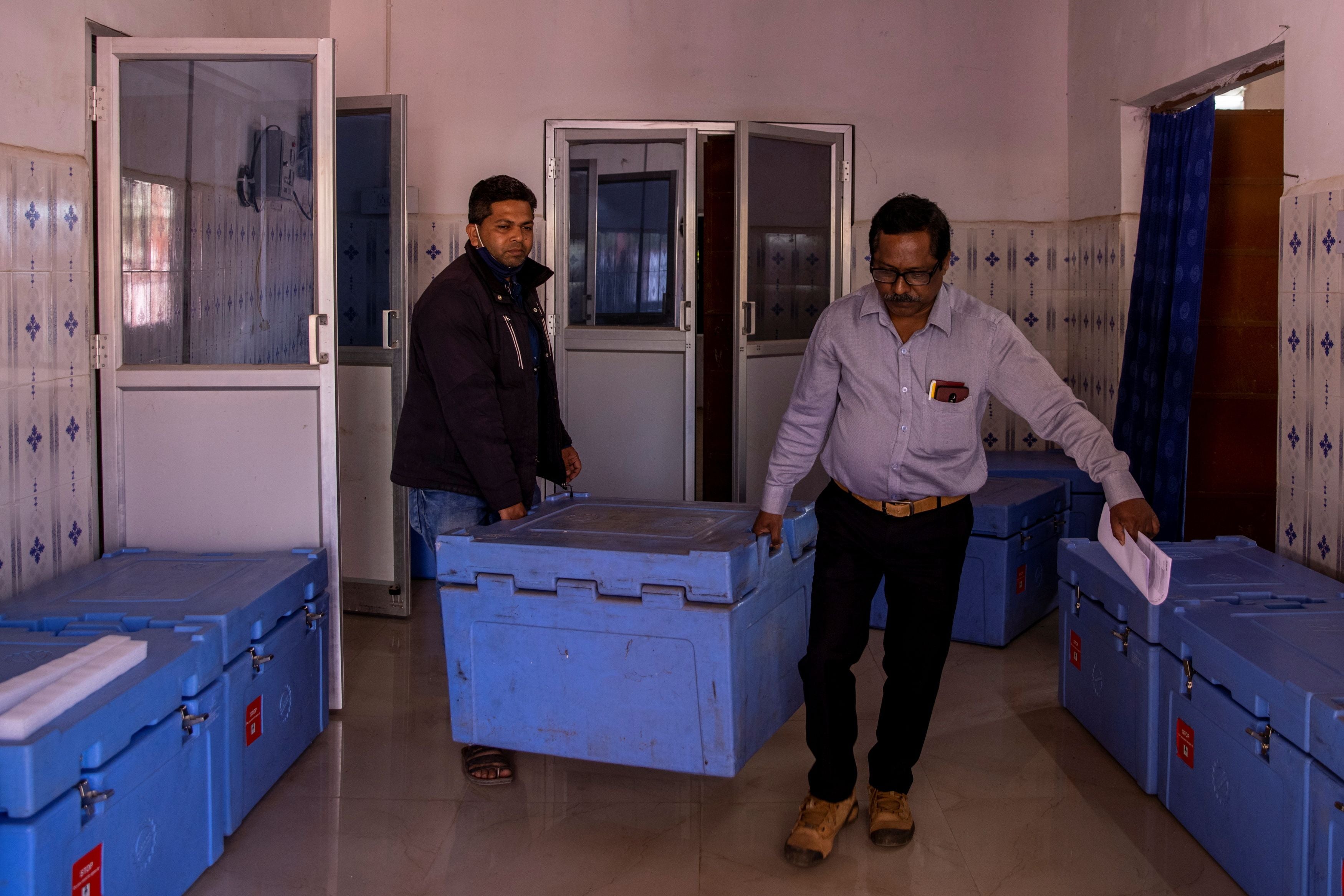 Health workers carry a box containing the vaccine