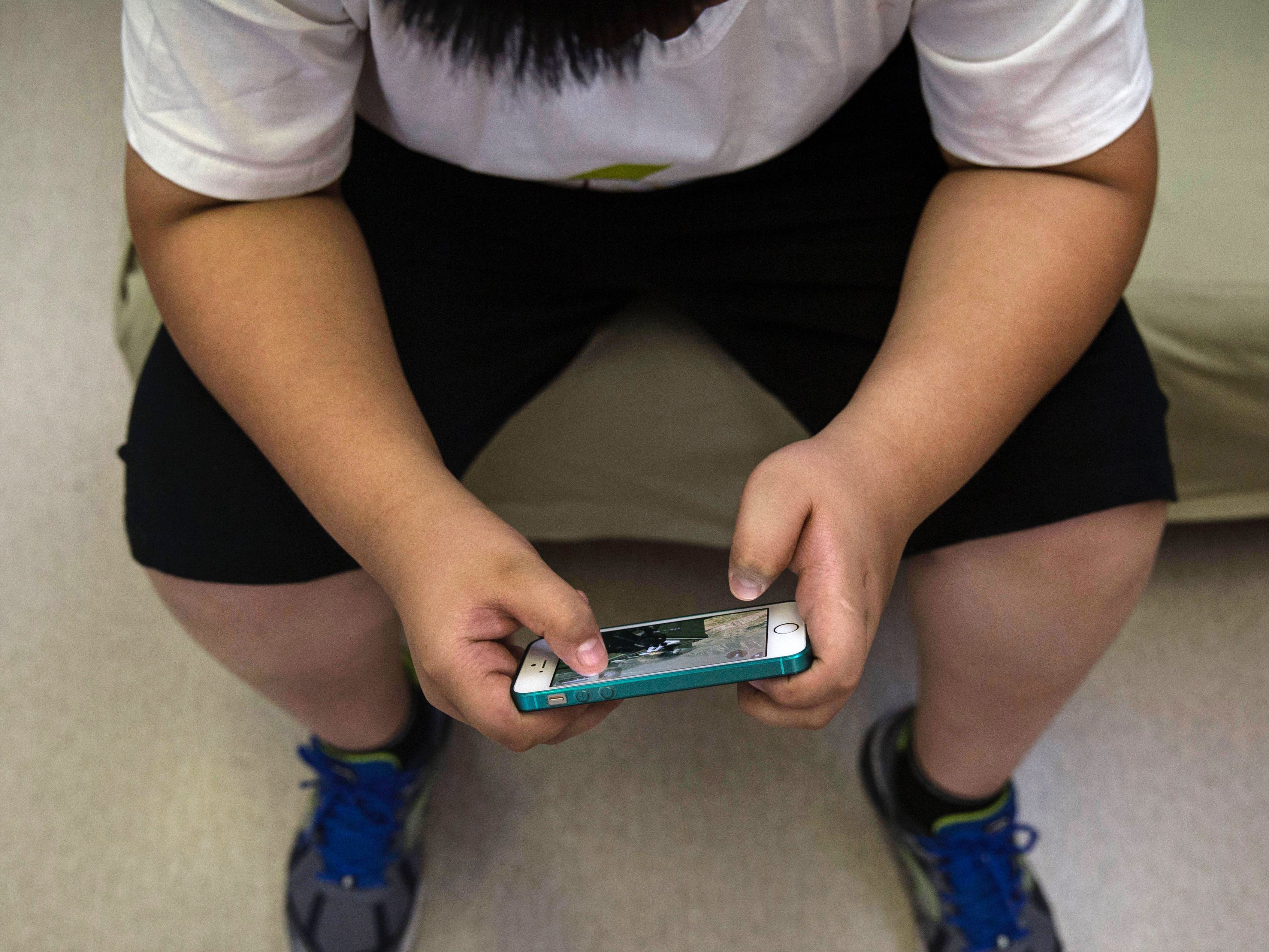 A Chinese student plays a game on his mobile phone