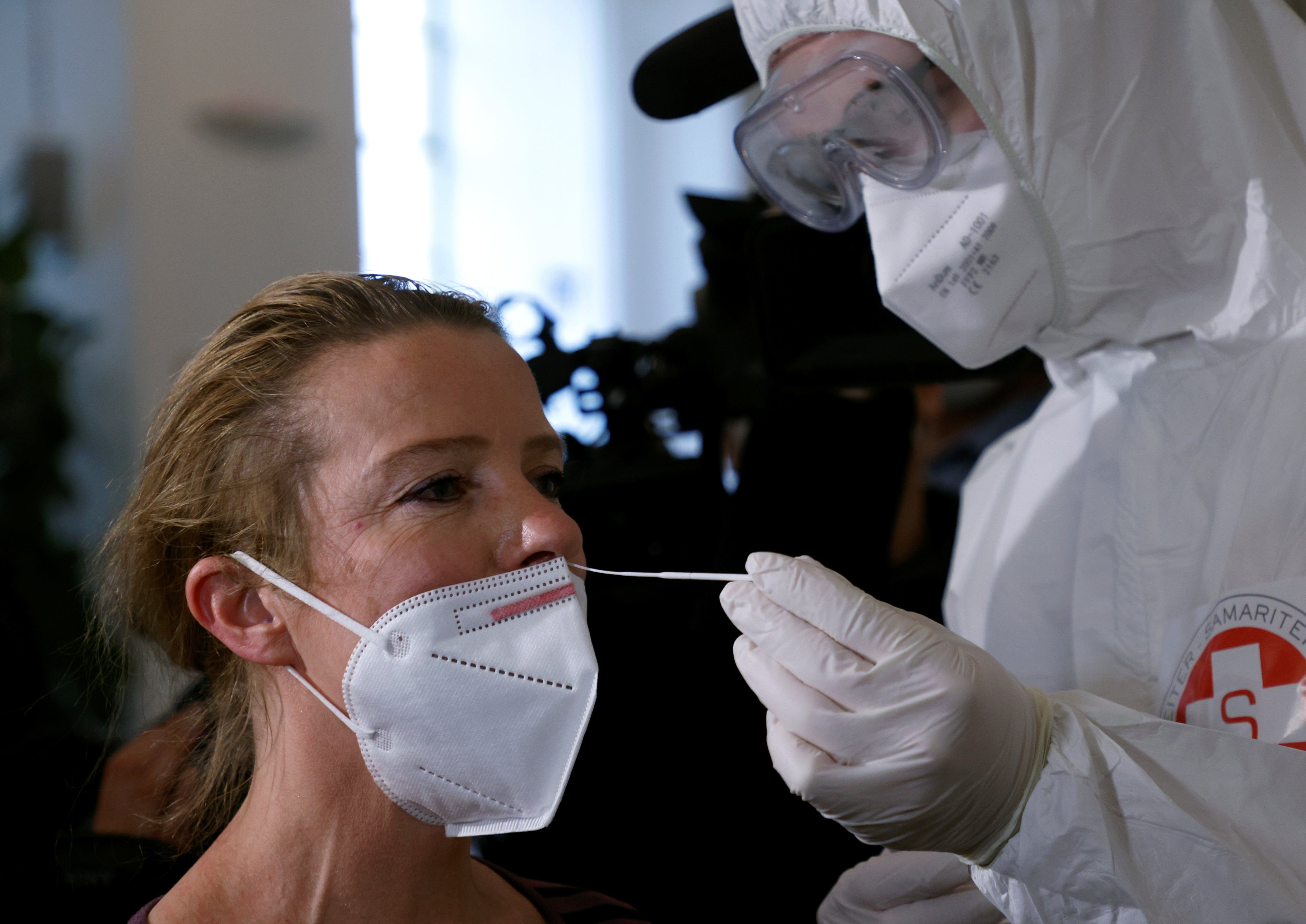 A healthcare worker in protective equipment takes a swab sample at a rapid antigen mass testing station in Vienna