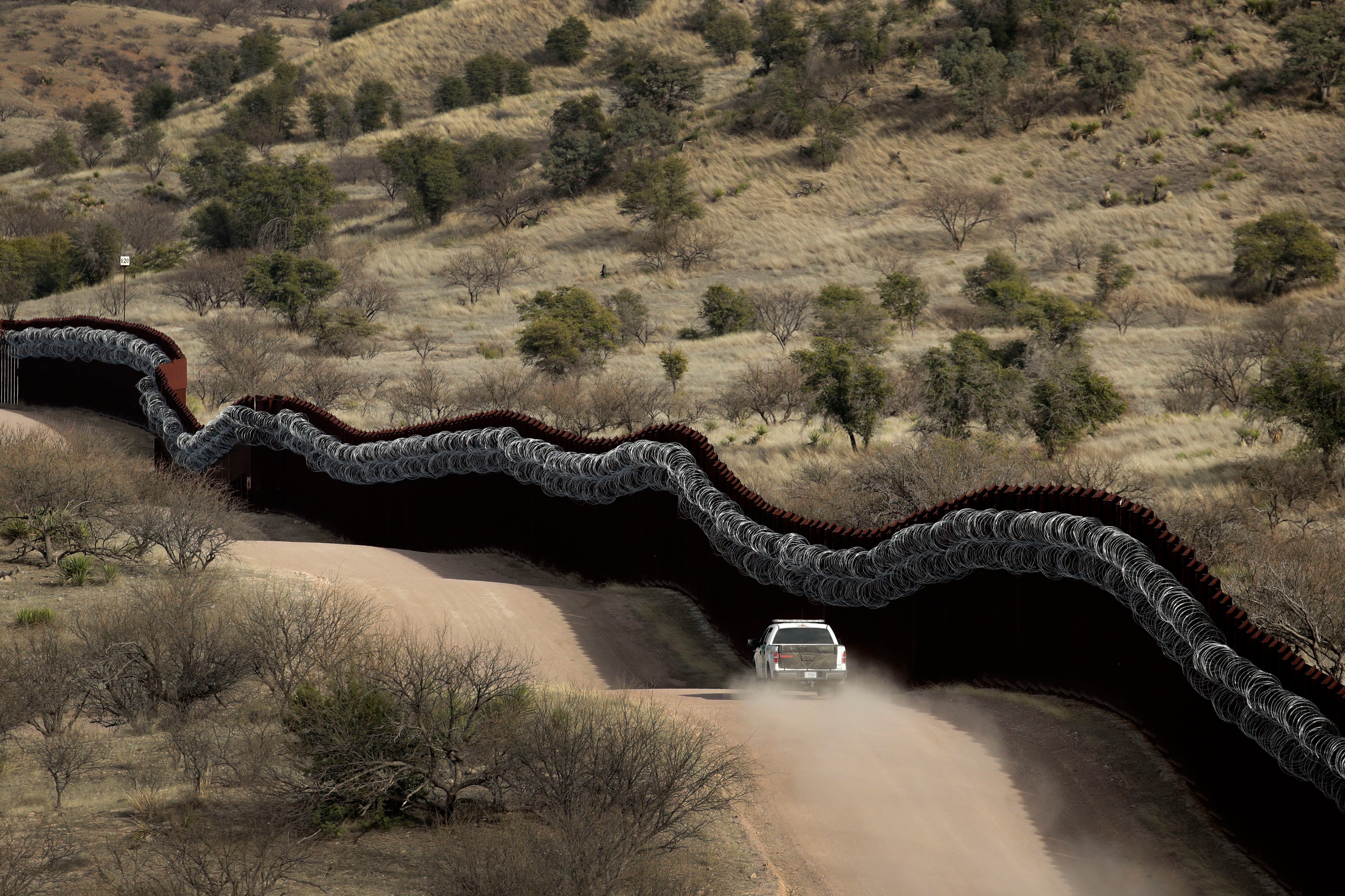 The US side of a wall covered with razor wire along the Mexican border east of Nogales, Arizona