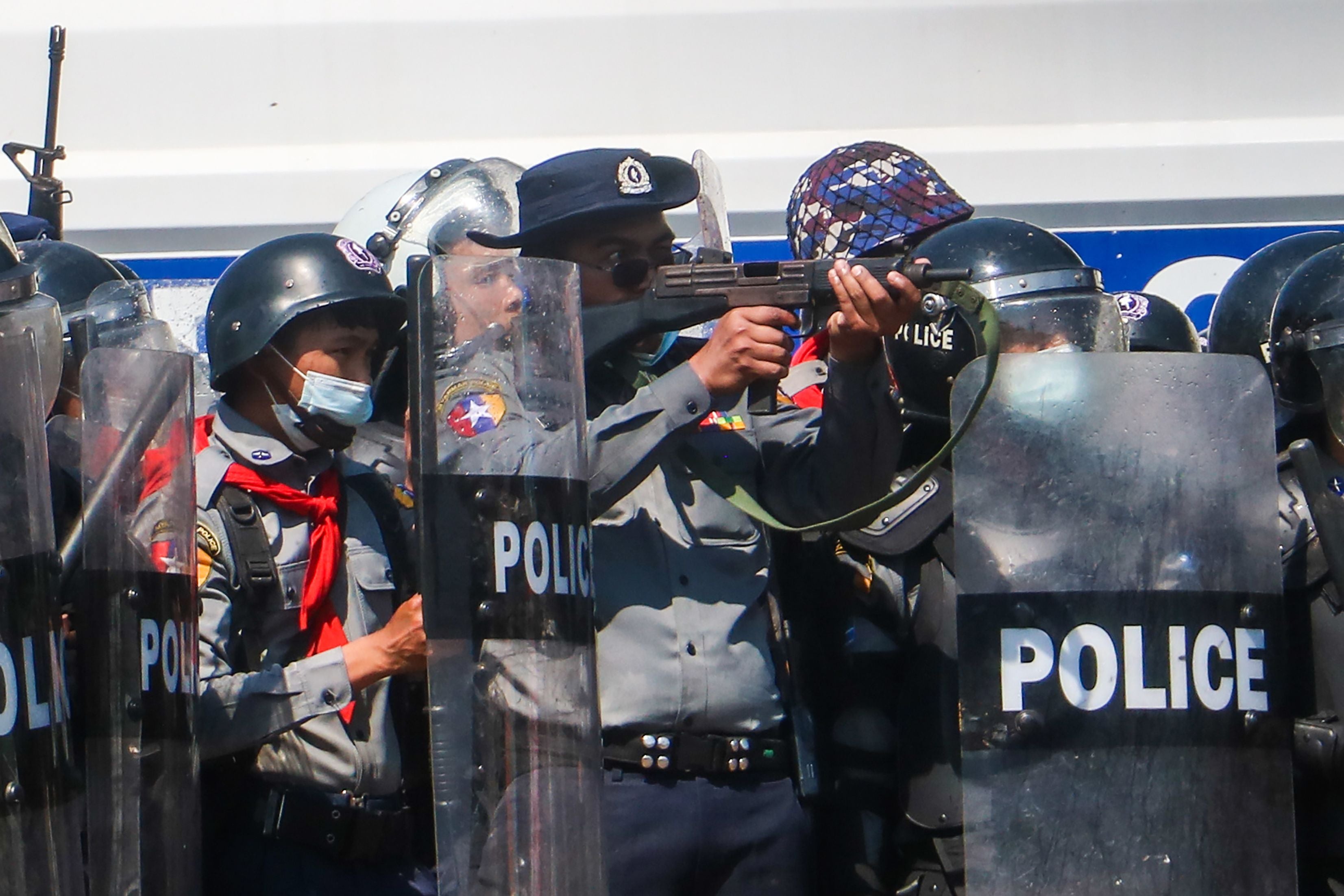 A police officer in Naypyidaw aims a gun during clashes with protesters taking part in a demonstration against a military coup in Myanmar