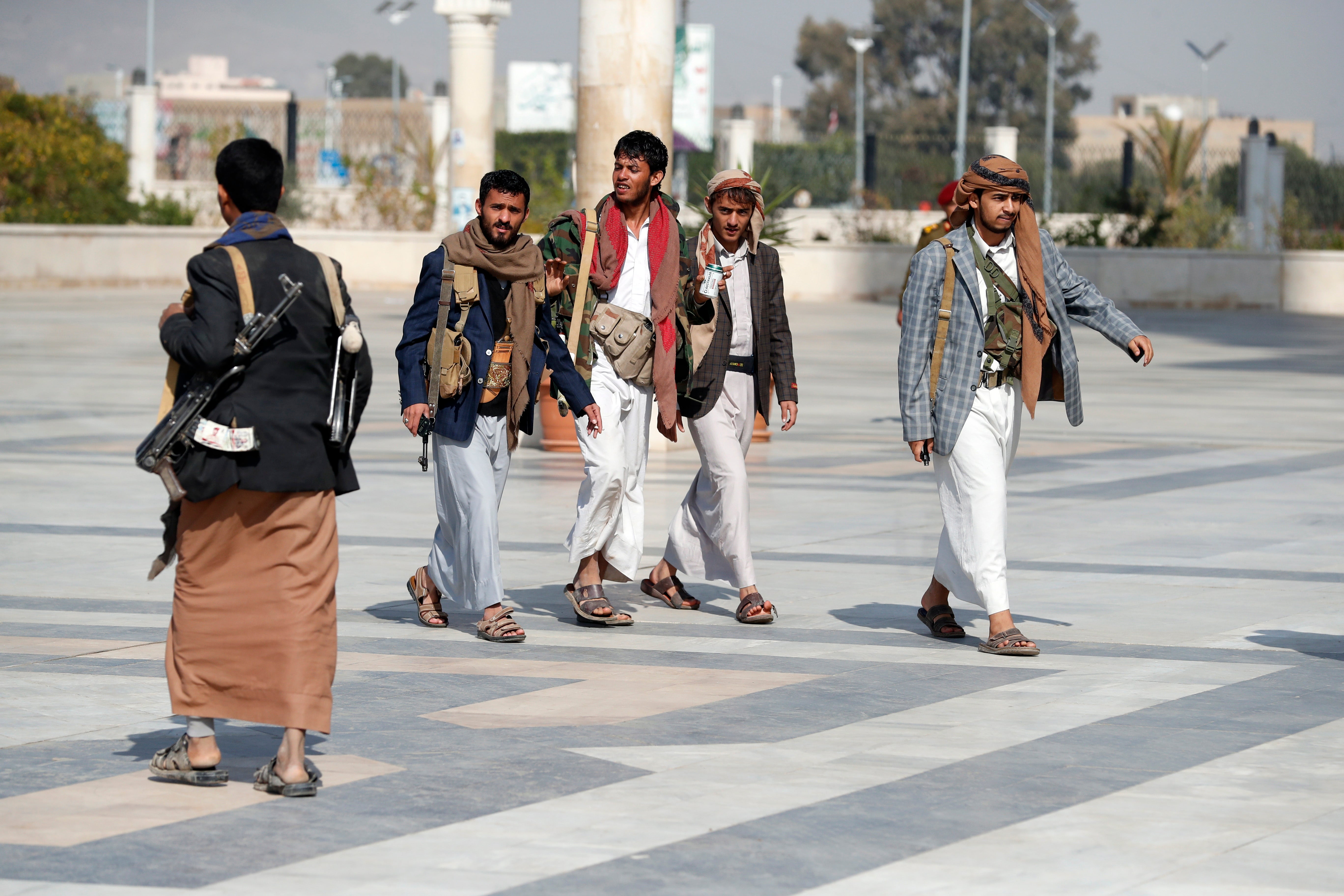 Armed Houthi supporters walk outside of a mosque in Sana'a