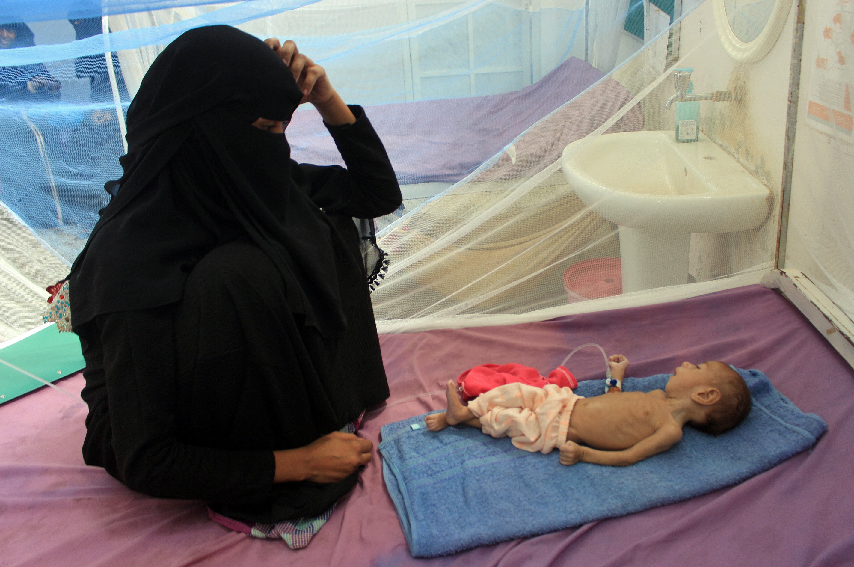 a Yemeni mother sits with her malnourished child during treatment at a medical centre in Yemen's northern Hajjah province