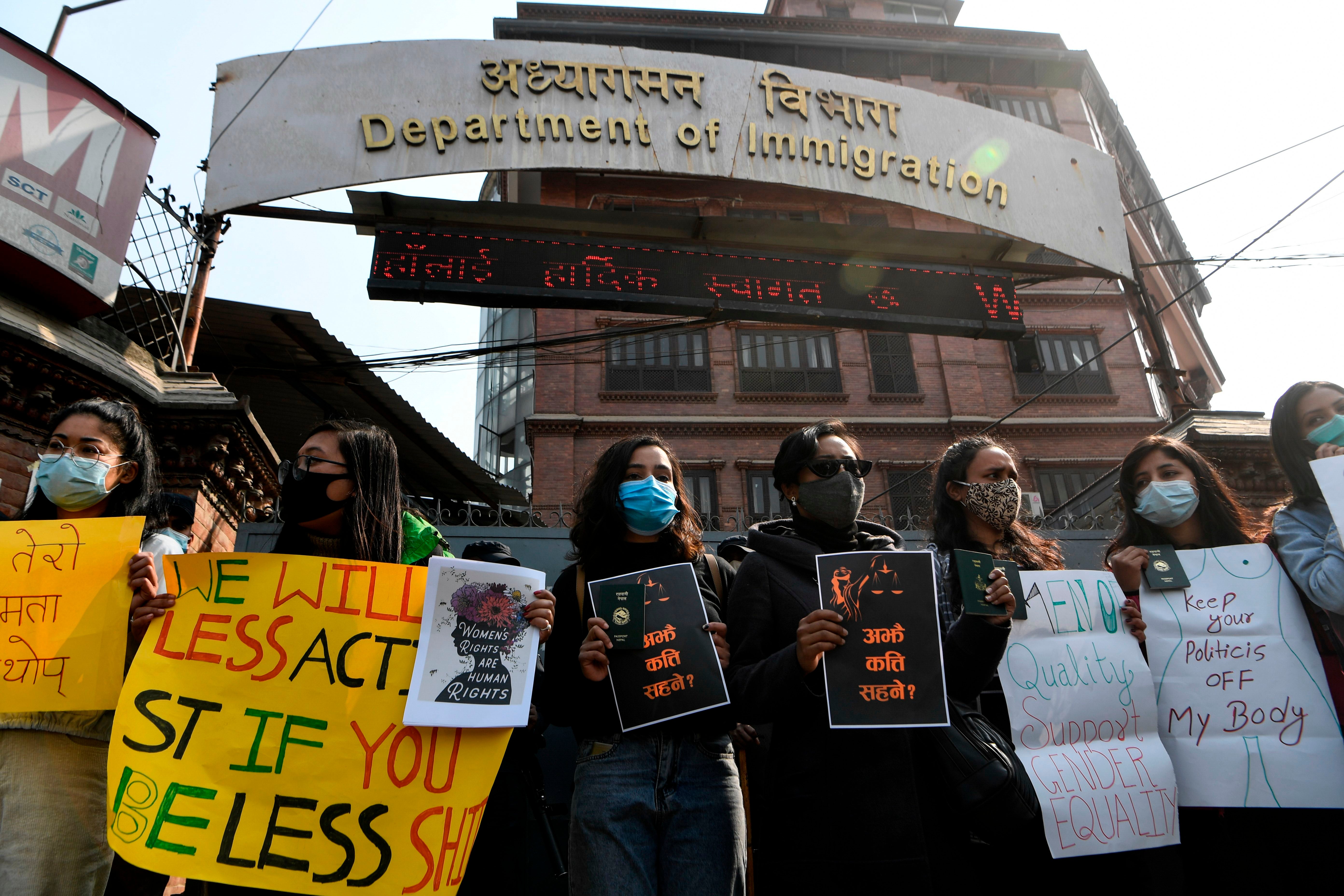 Women rights activists hold placards in front of Nepal’s Department of Immigration office during a protest against a proposed immigration rule that seeks family approval for abroad travel of women aged below 40, in Kathmandu on 11 February, 2021.