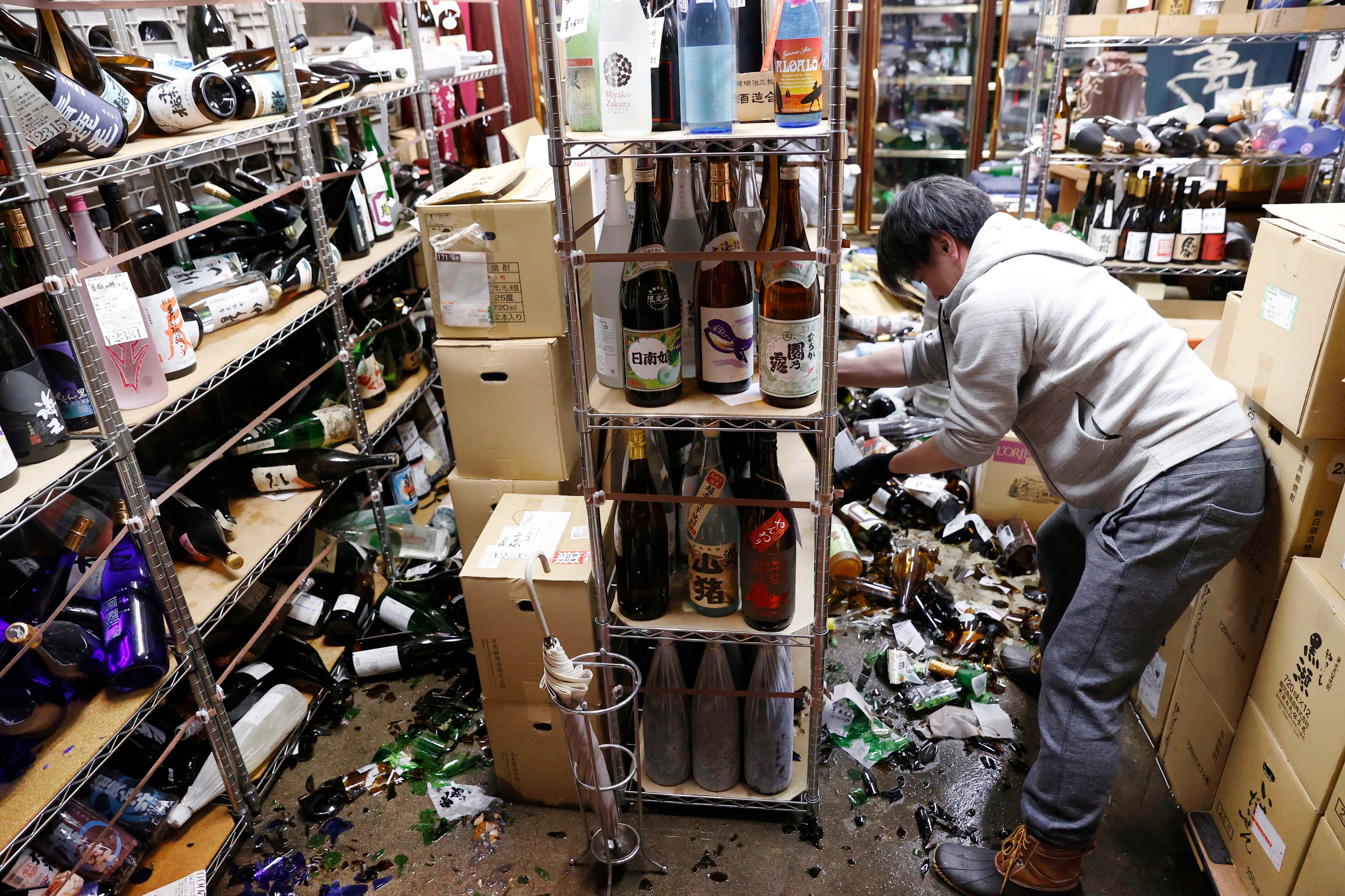 A liquor shop's manager clears the damaged bottles following an earthquake in Fukushima, northeastern Japan