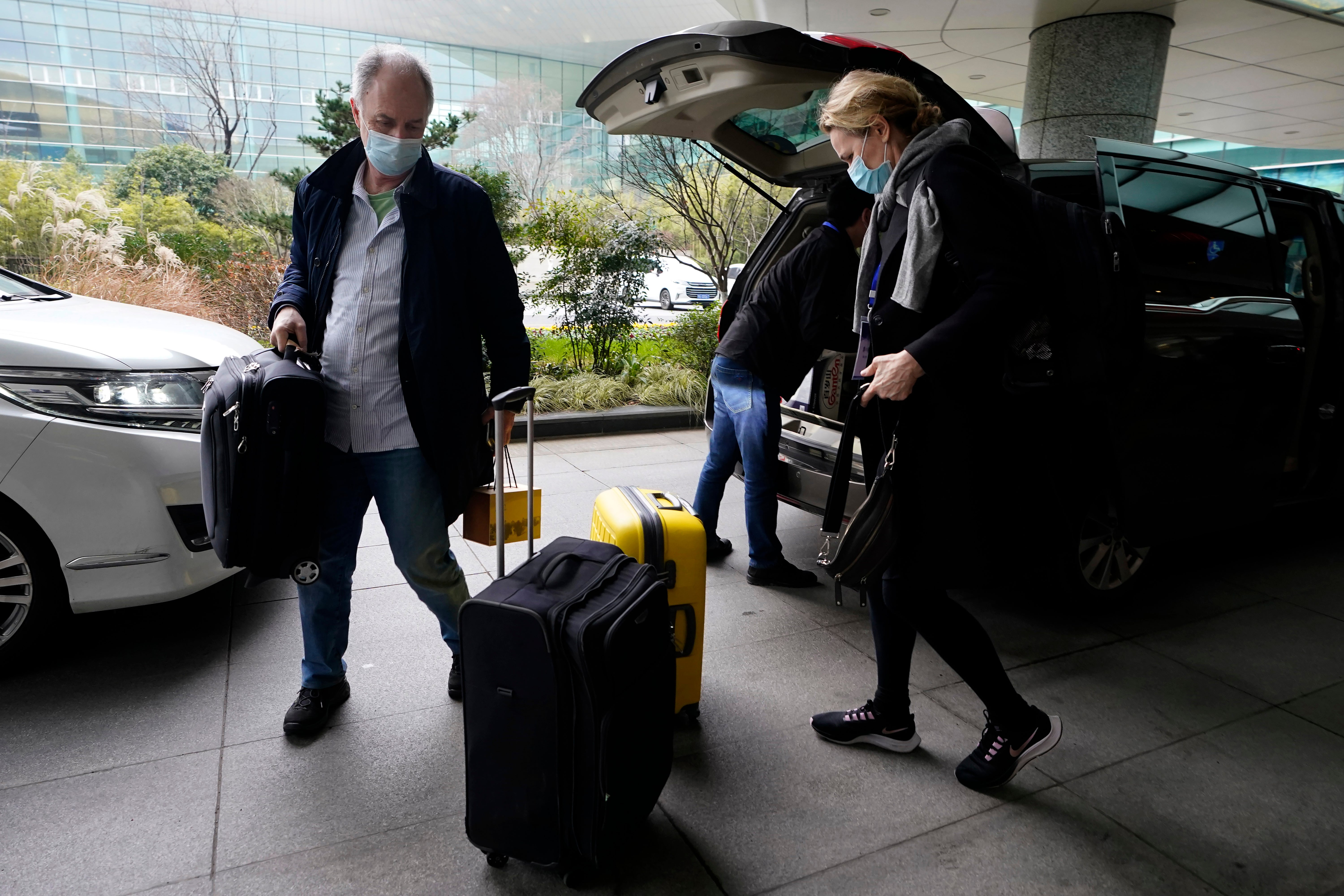 John Watson, left, arrives at the airport to leave at the end of the WHO mission in Wuhan