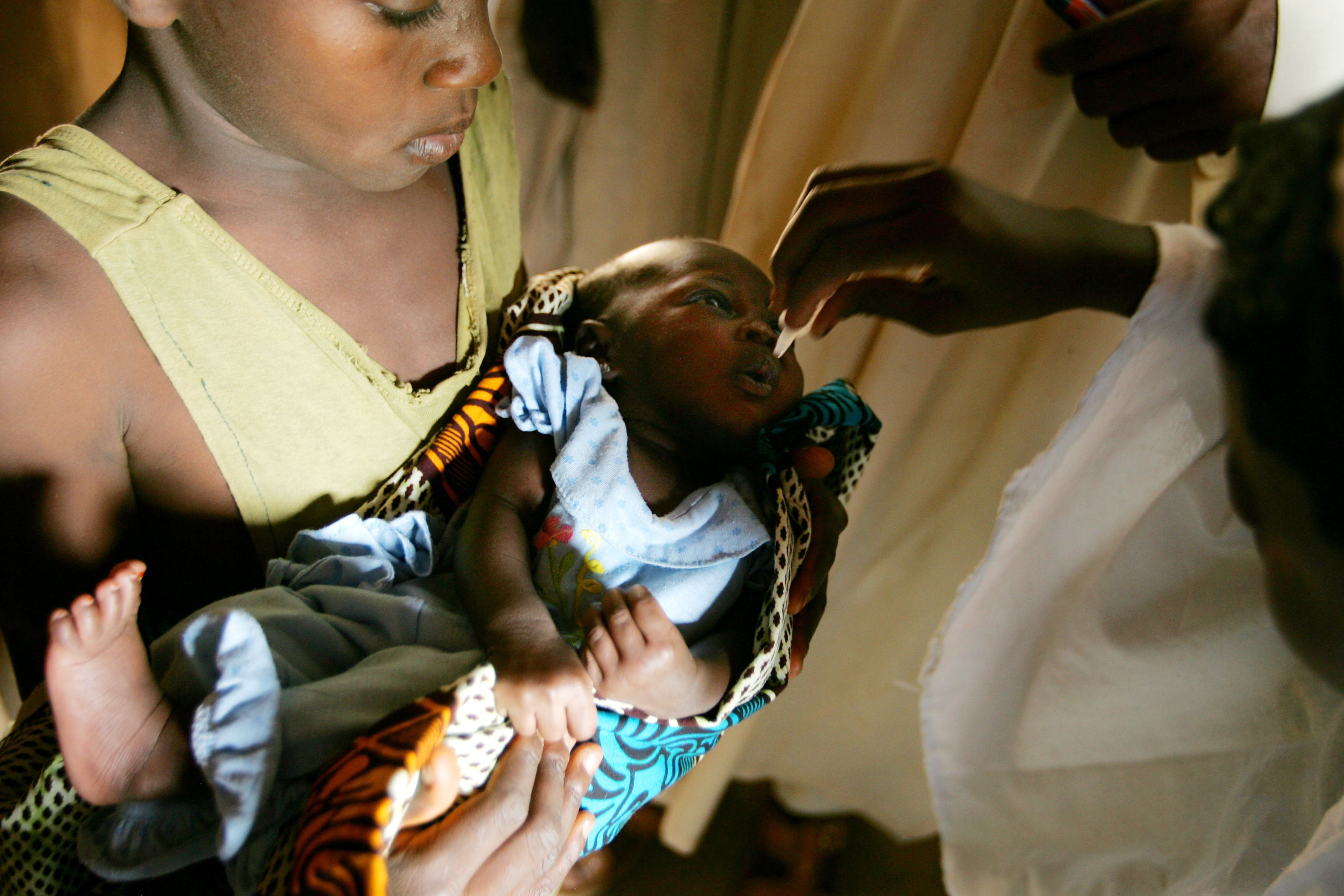 Nigerian WHO field workers inoculating a child with the polio vaccine