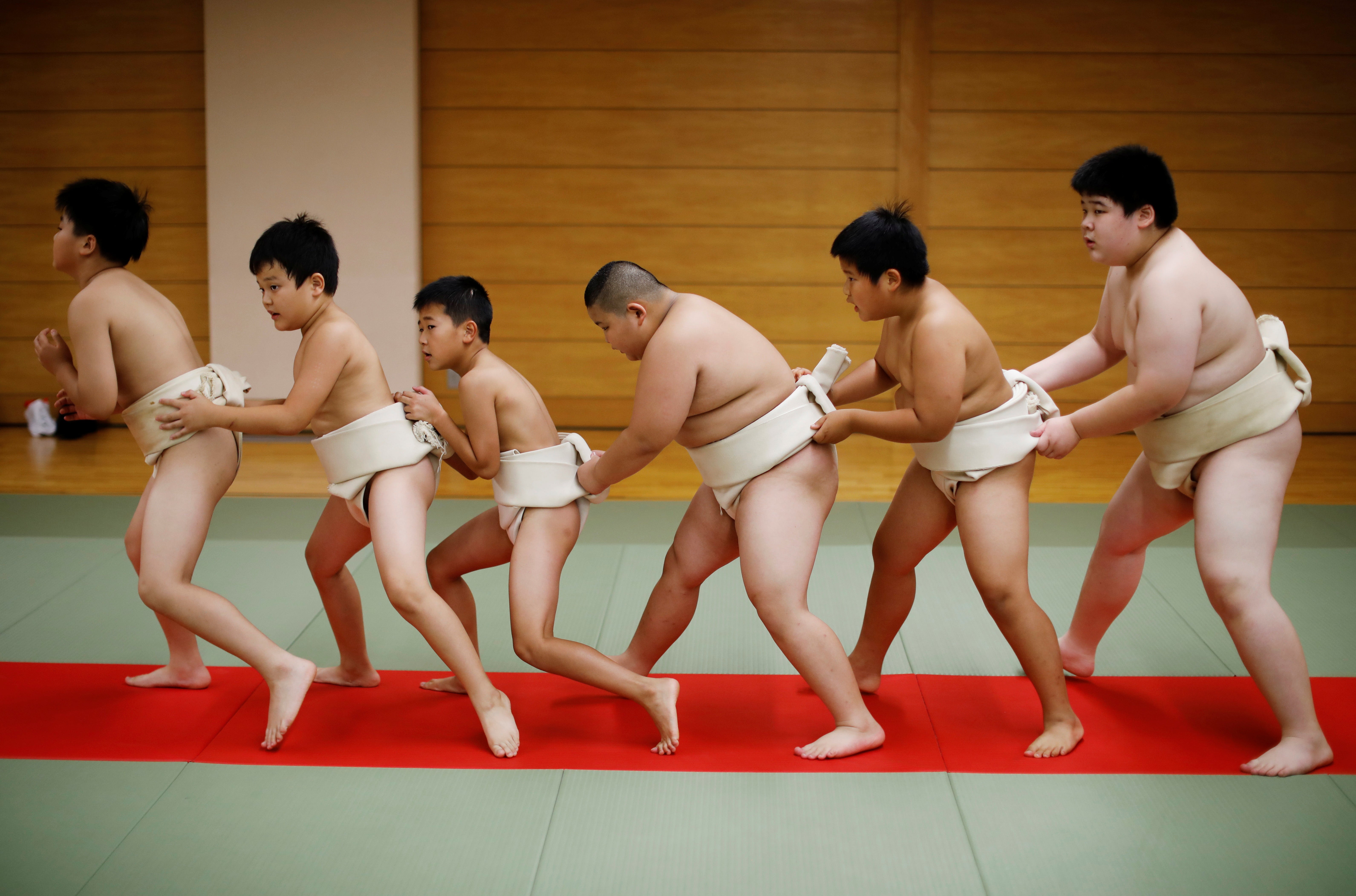 Kyuta, centre, warms up with other boys before training, at Komatsuryu sumo club, Tokyo, in August of last year