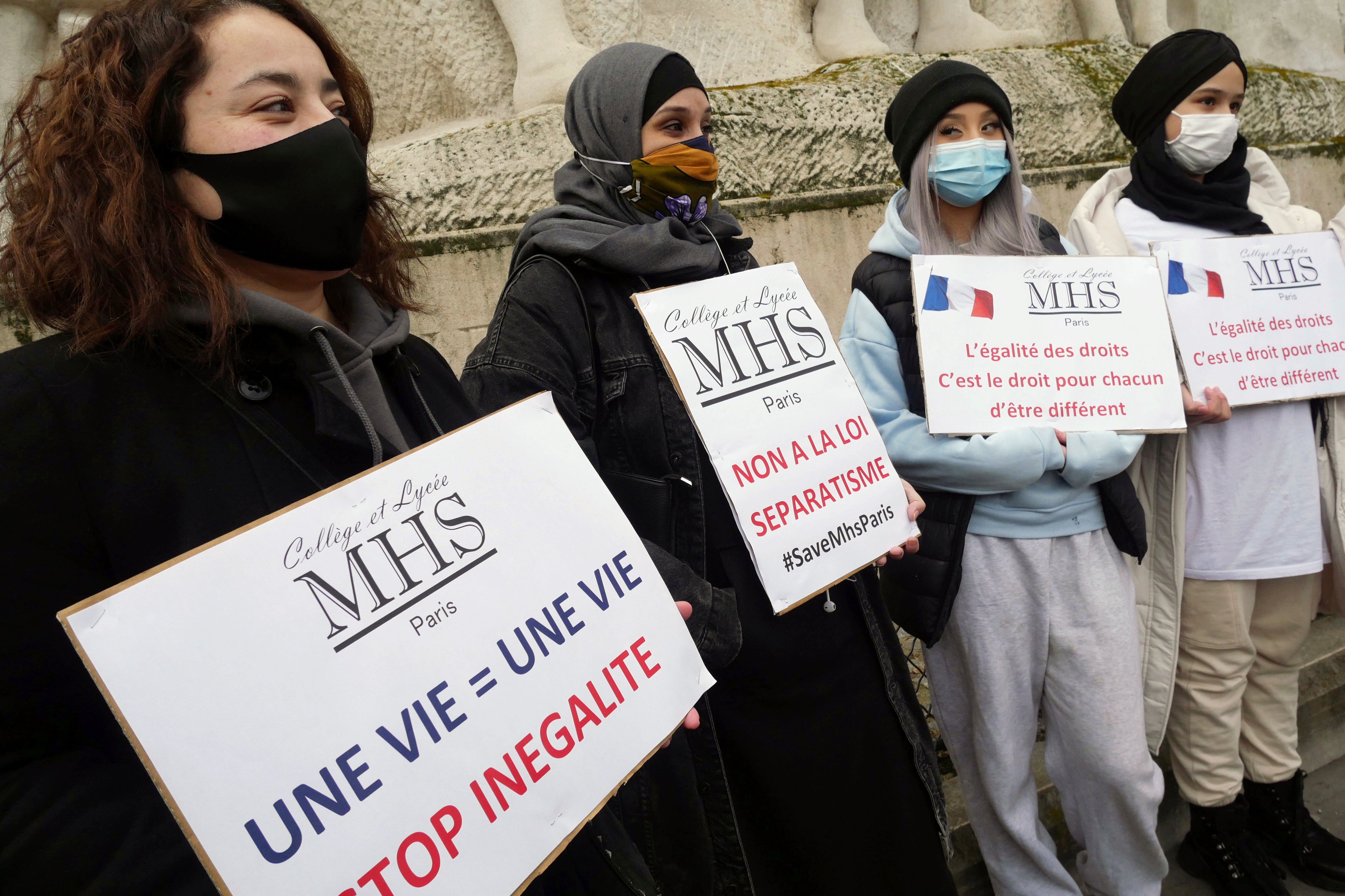 Activists hold placards reading 'No to the separatism law’ in the center, and ‘Equality of rights is the right of everyone to be different’ on the right, during a gathering in Paris on Sunday