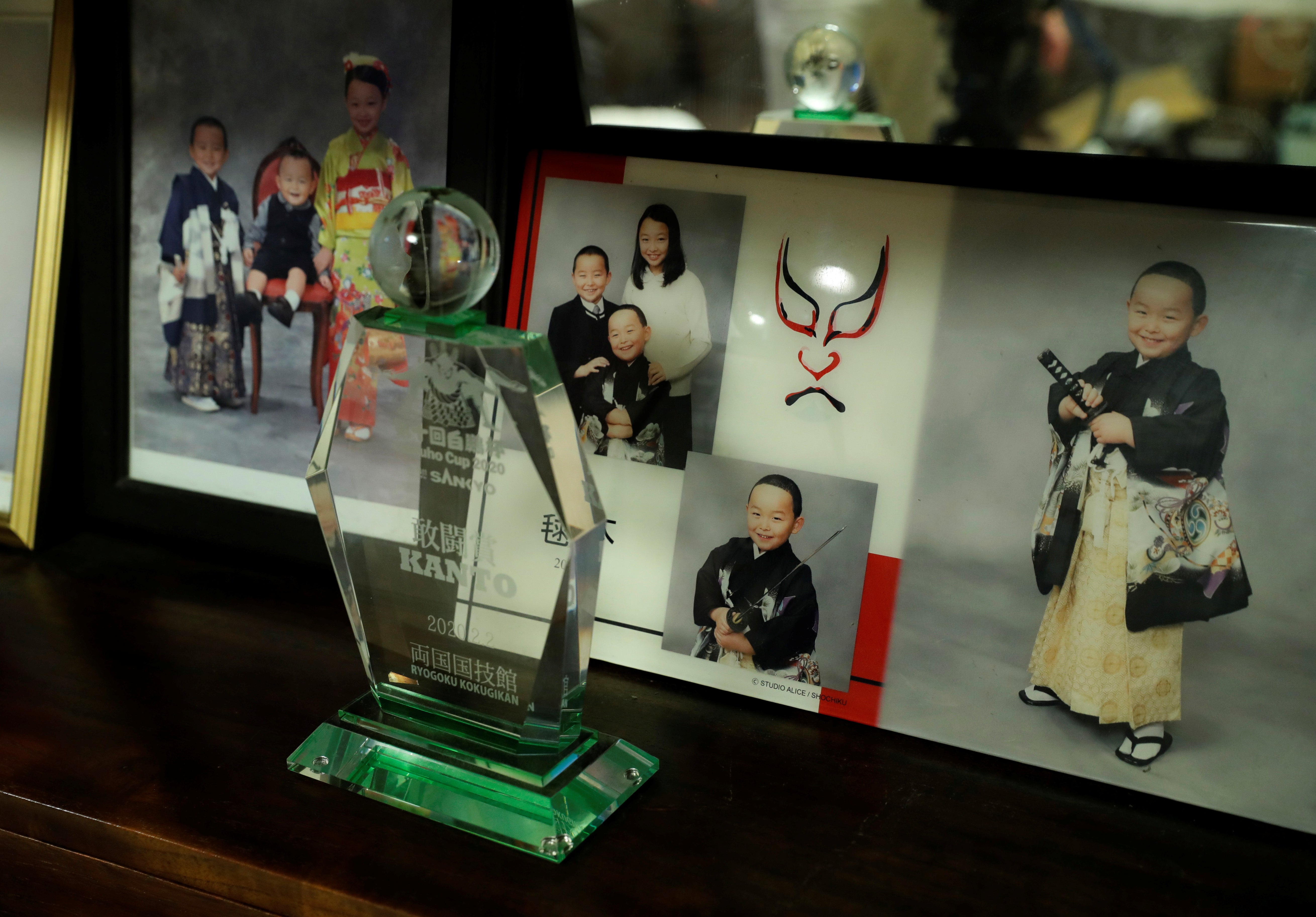 A trophy, which Kyuta won at the Hakuho Cup 2020 sumo tournament, is displayed in front of family photos in the living room of Kumagai’s home in Tokyo