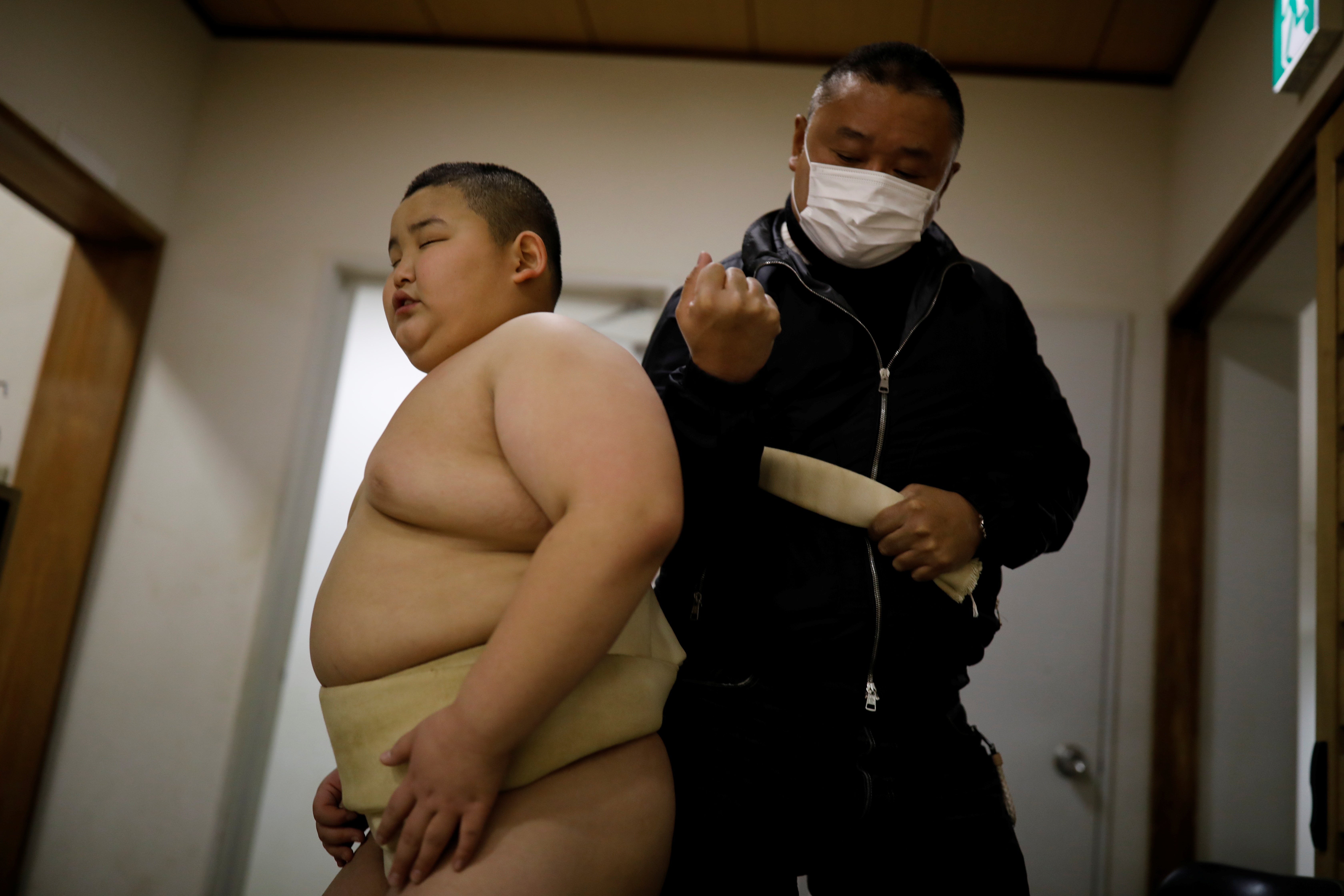 Taisuke Kumagai, 50, adjusts his son Kyuta's loincloth called a mawashi, during a training session at Komatsuryu sumo club