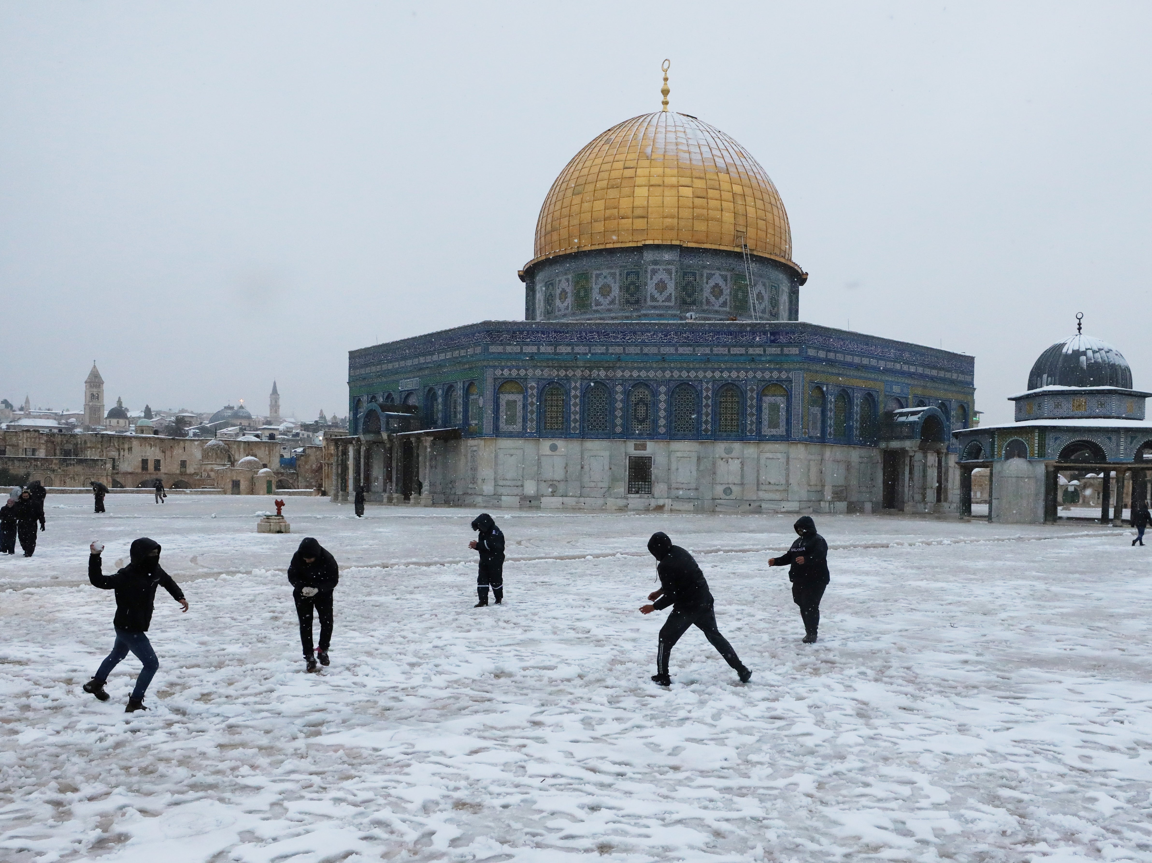 People play by the Dome of the Rock on the compound known to Jews as Temple Mount and to Muslims as Noble Sanctuary during a snowy morning in Jerusalem's Old City