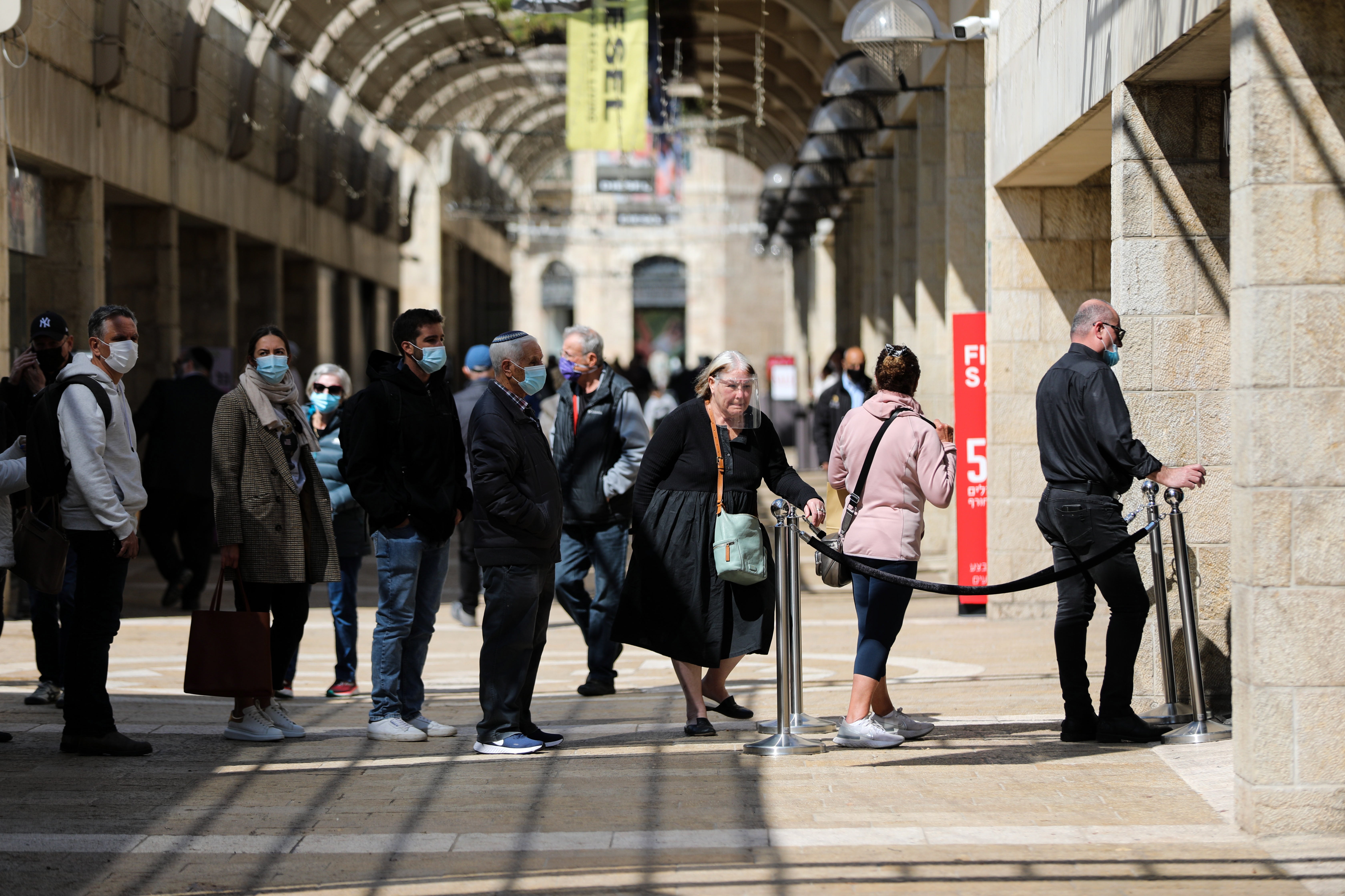 People queue to enter a shop in Jerusalem on Sunday after Israel reopened cultural hubs and shopping malls