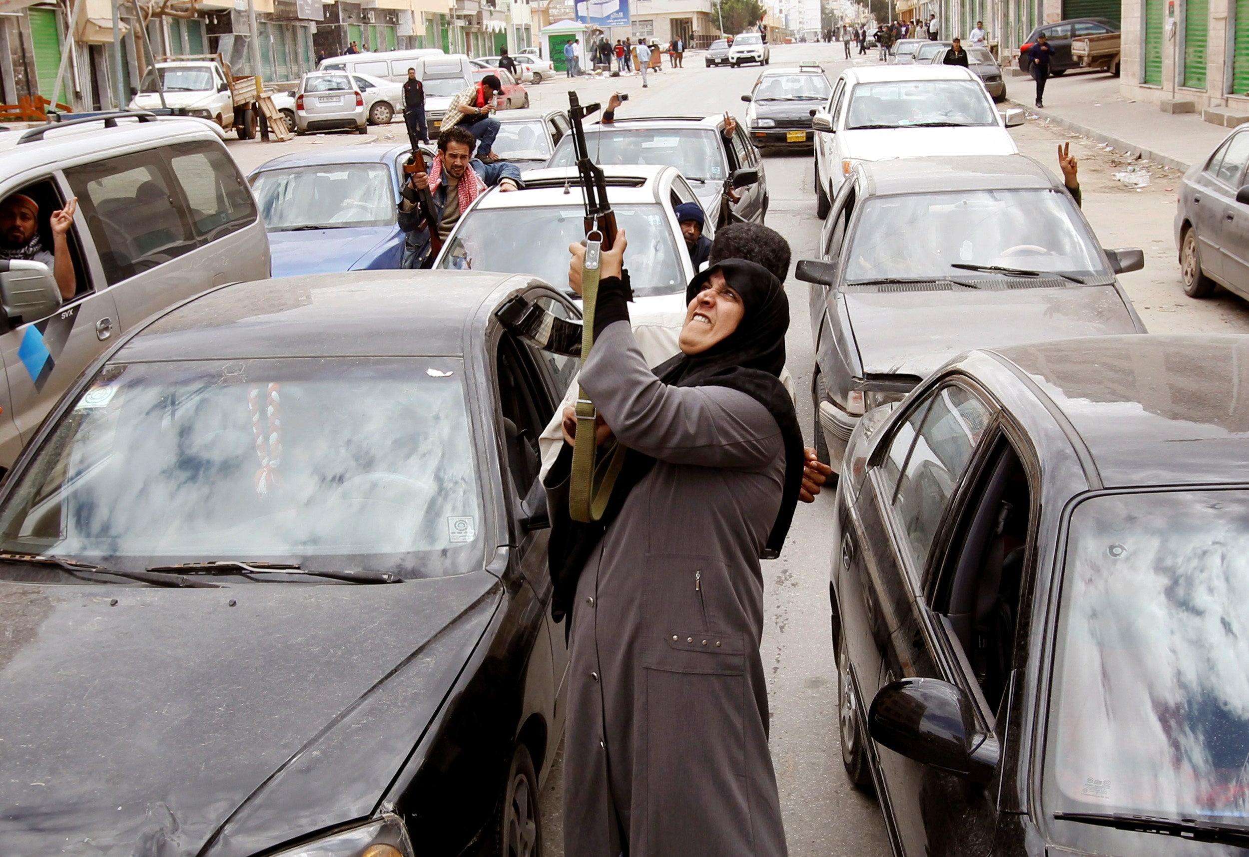 A woman rebel fighter supporter shoots an AK-47 rifle as she reacts to the news of the withdrawal of Libyan leader Muammar Gaddafi's forces from Benghazi March 19, 2011