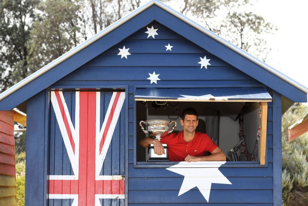 Novak Djokovic poses with the Norman Brookes Challenge Cup trophy on Brighton Beach in Melbourne