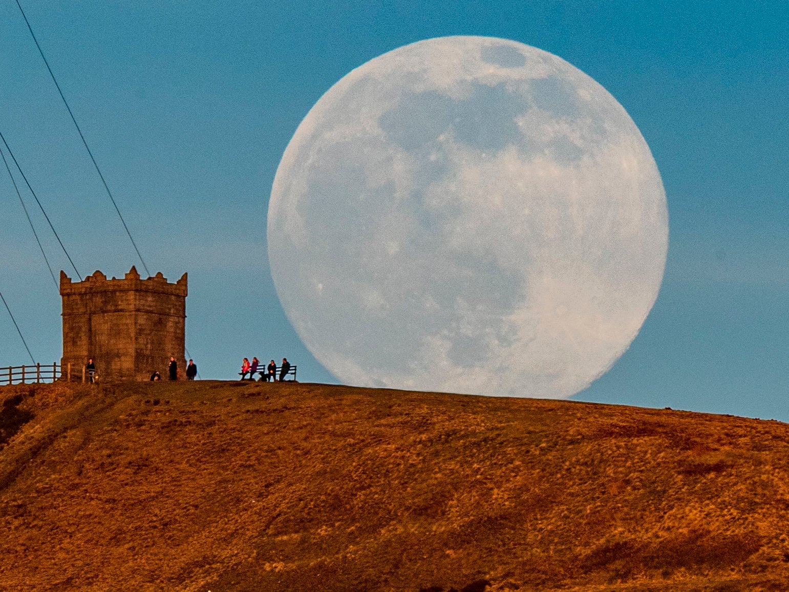 A snow moon rises behind Rivington Pike near Bolton, Greater Manchester in 2021