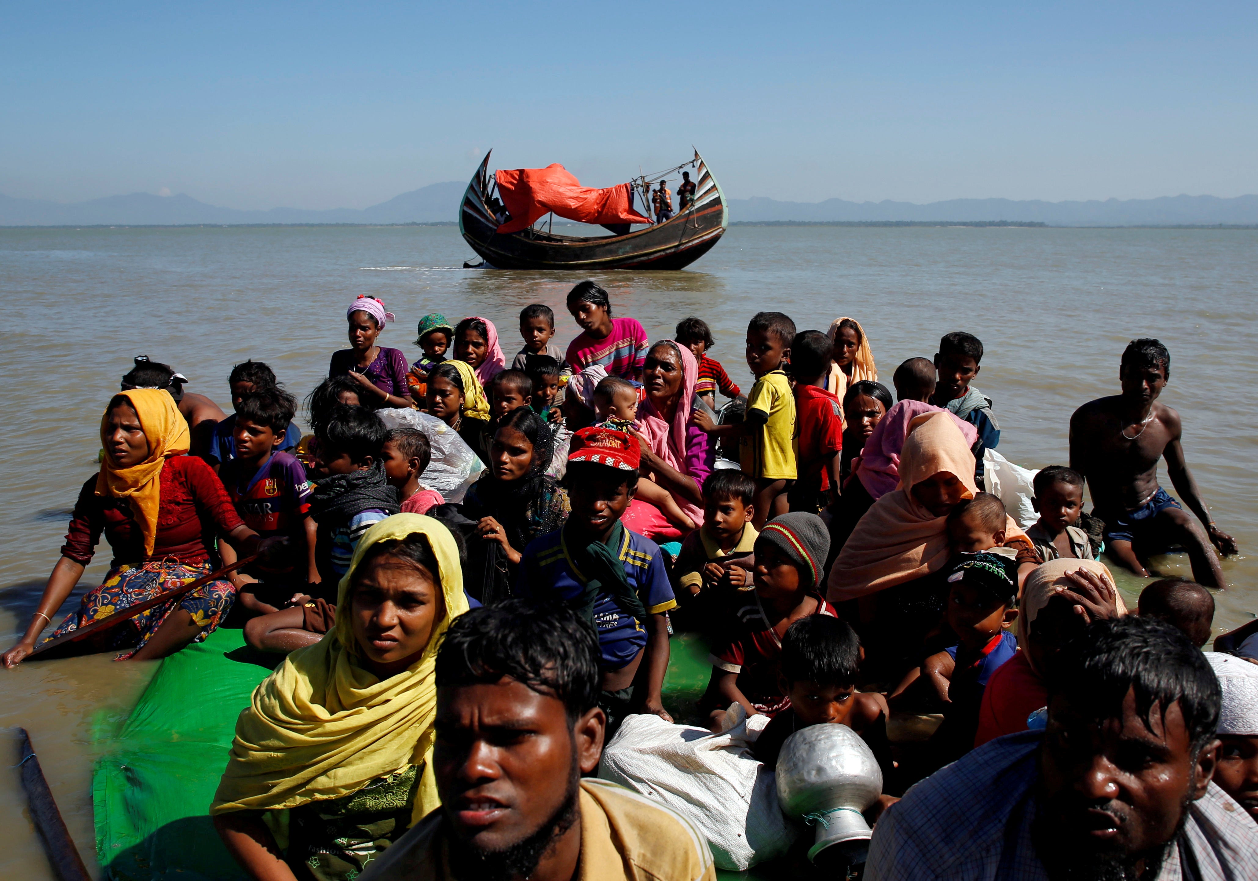 Rohingya refugees sit on a makeshift boat as they are interrogated by the Bangladeshi border guard after crossing the Bangladesh-Myanmar border, at Shah Porir Dwip near Cox’s Bazar