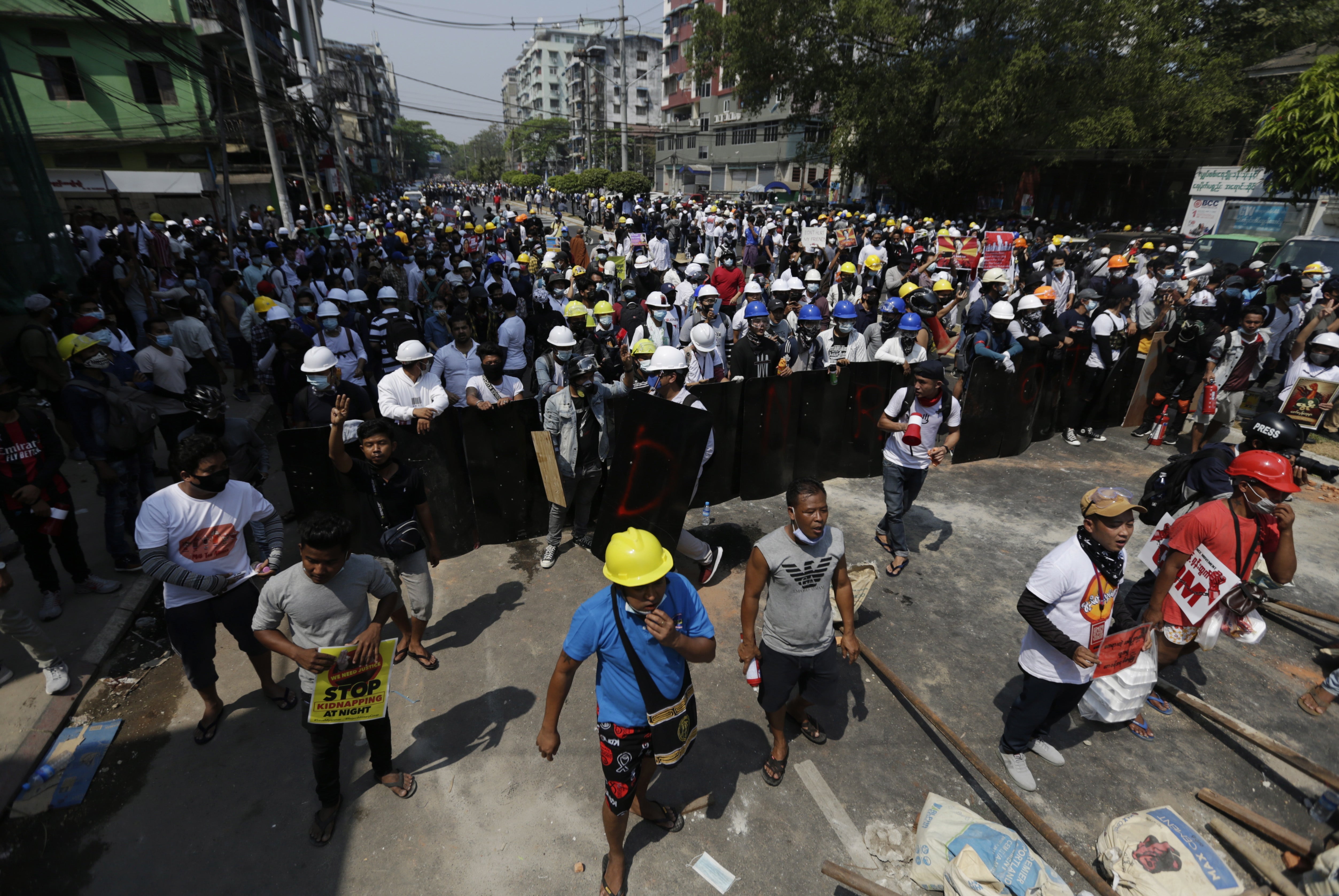 Demonstrators hold shields as they face riot police