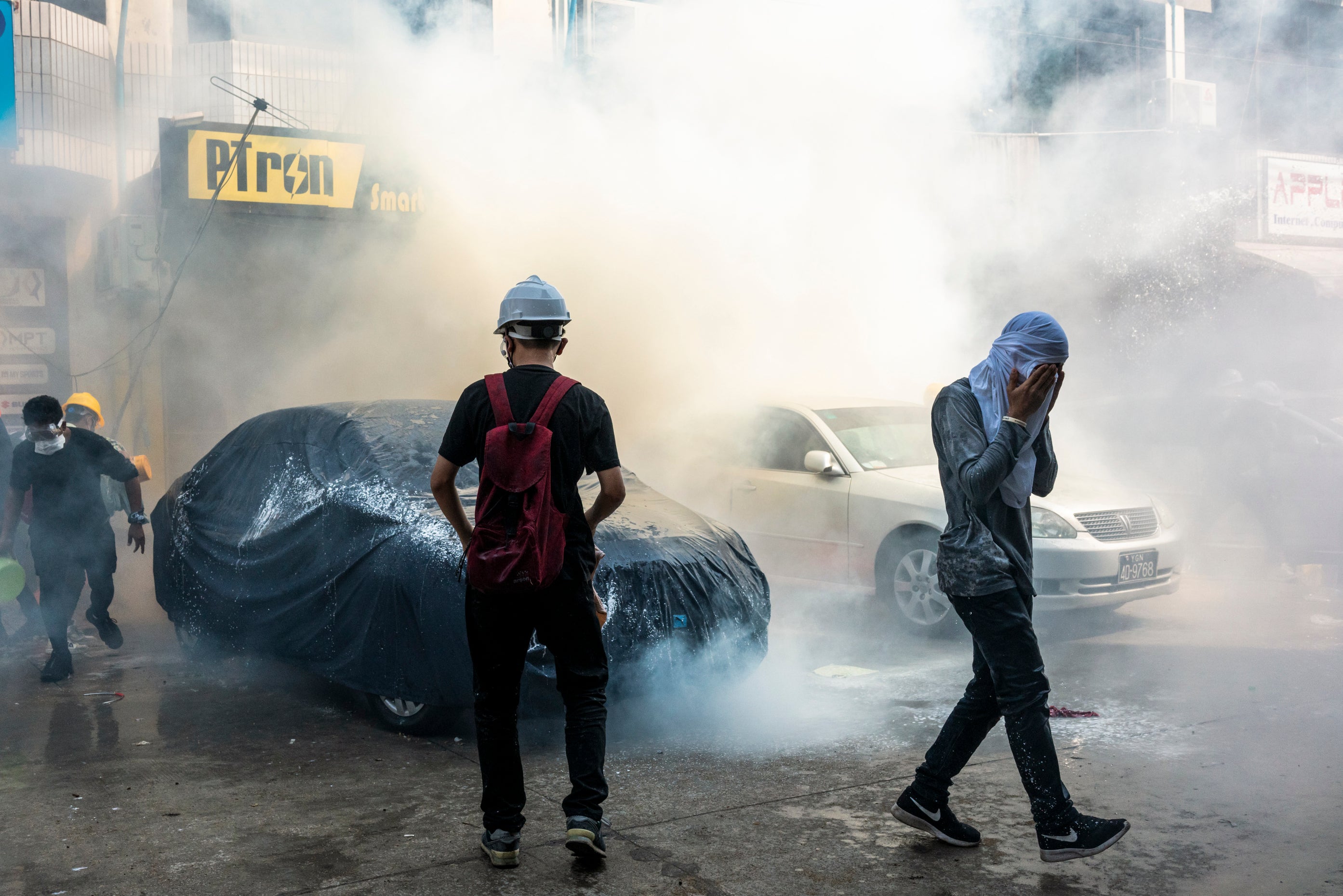 Protesters attempt to put out a tear gas canister fired by riot police