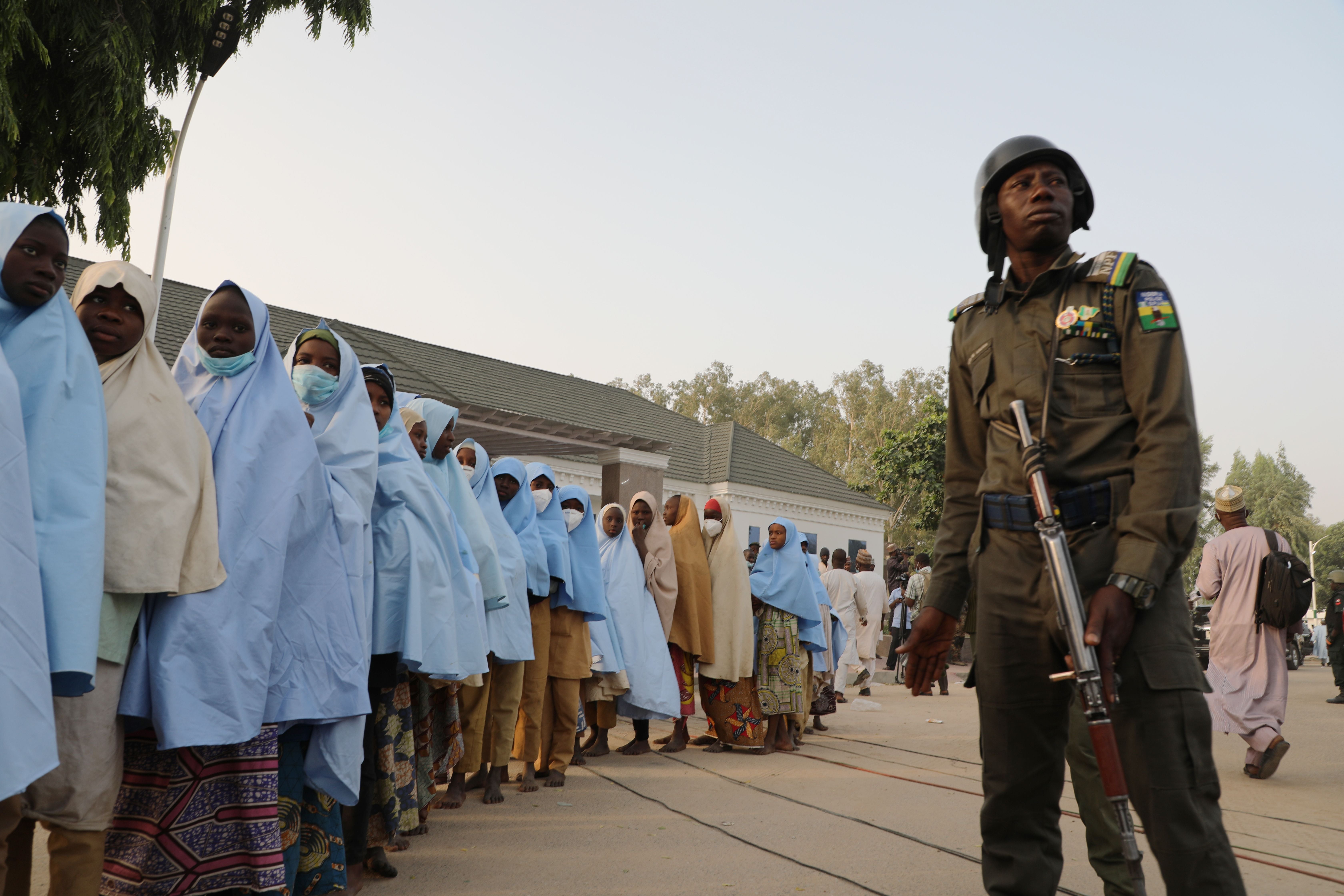 A soldiers stands next to a group of girls previously kidnapped from their boarding school in Zamfara state