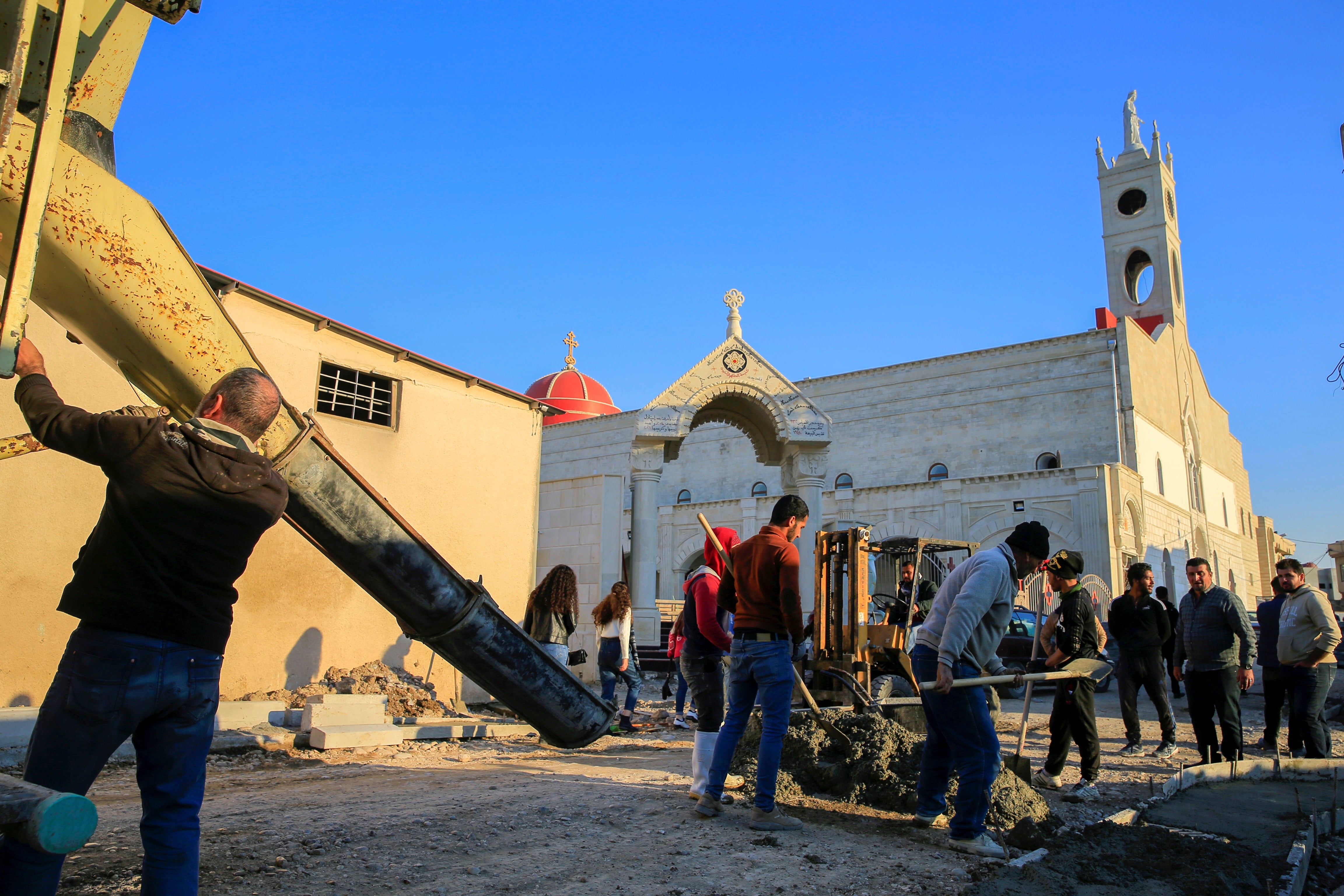 Workers repair a damaged street near the Grand Immaculate Church, ahead of the planned visit of Pope Francis to Iraq