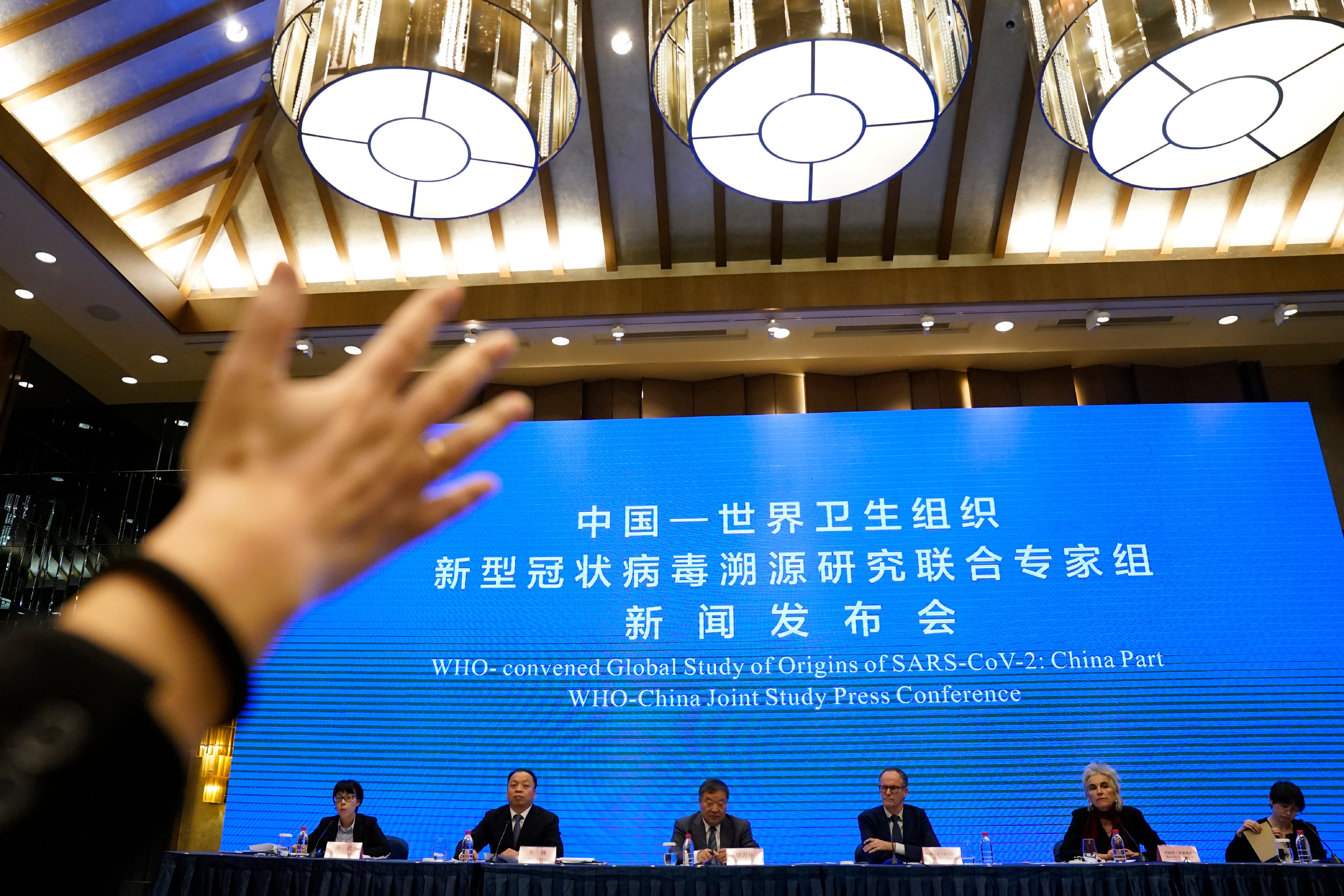A journalist raises her hand to ask a question at the WHO-China Joint Study Press Conference held at the end of the World Health Organization mission in Wuhan, China