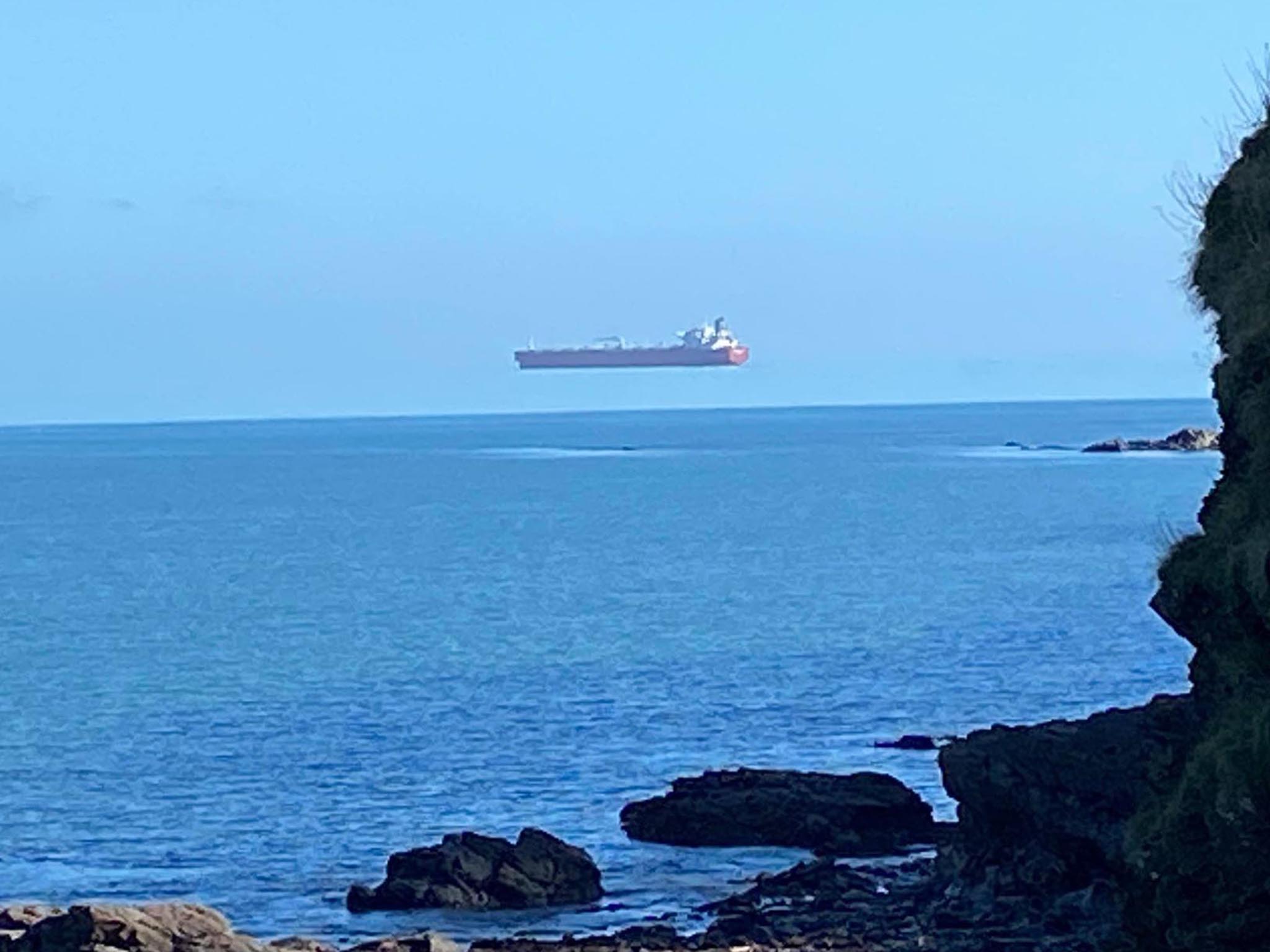 A tanker appears to float above the sea when viewed from the Cornwall coast