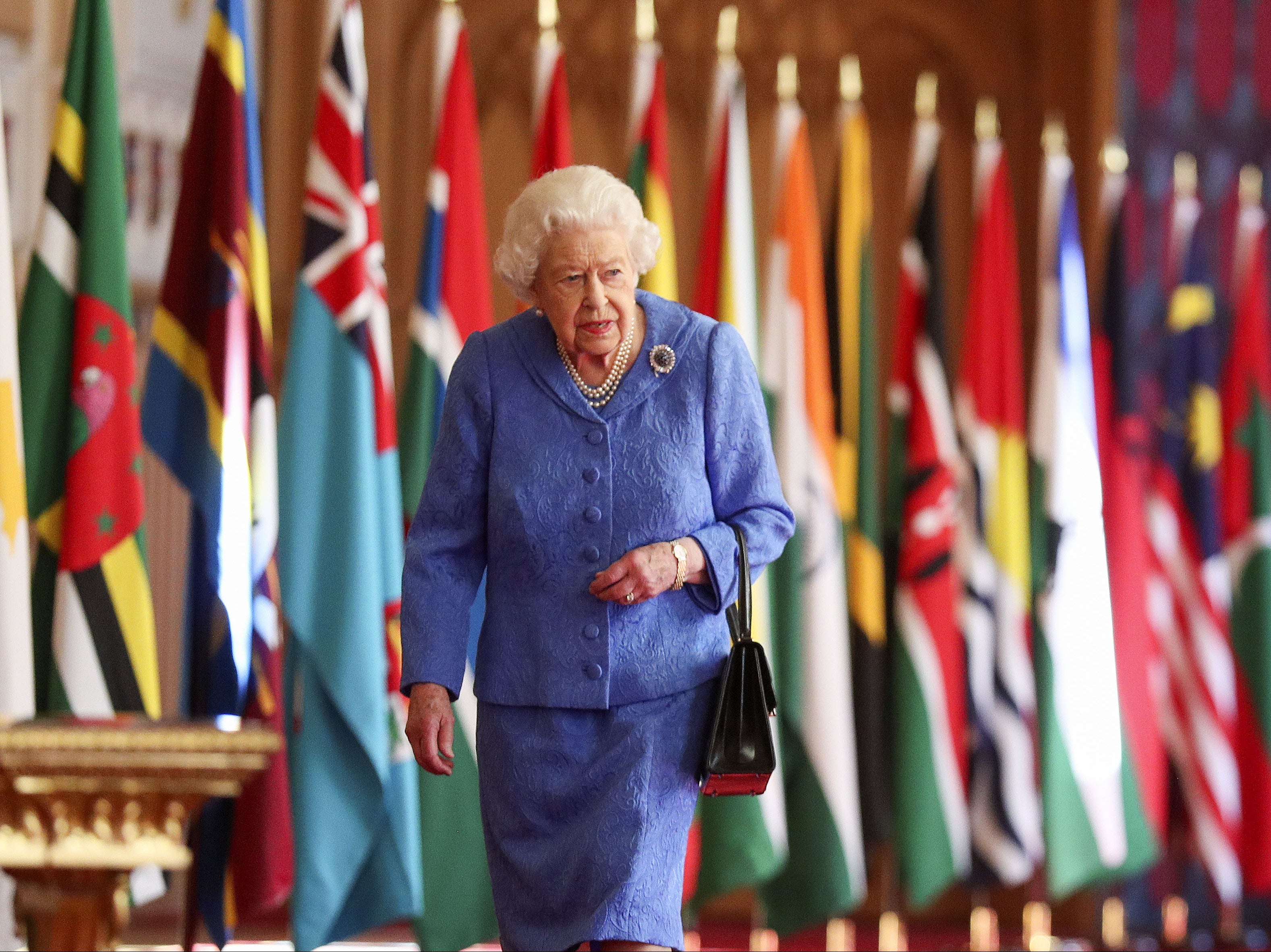 Queen Elizabeth II walks past Commonwealth flags in St George's Hall at Windsor Castle , to mark Commonwealth Day