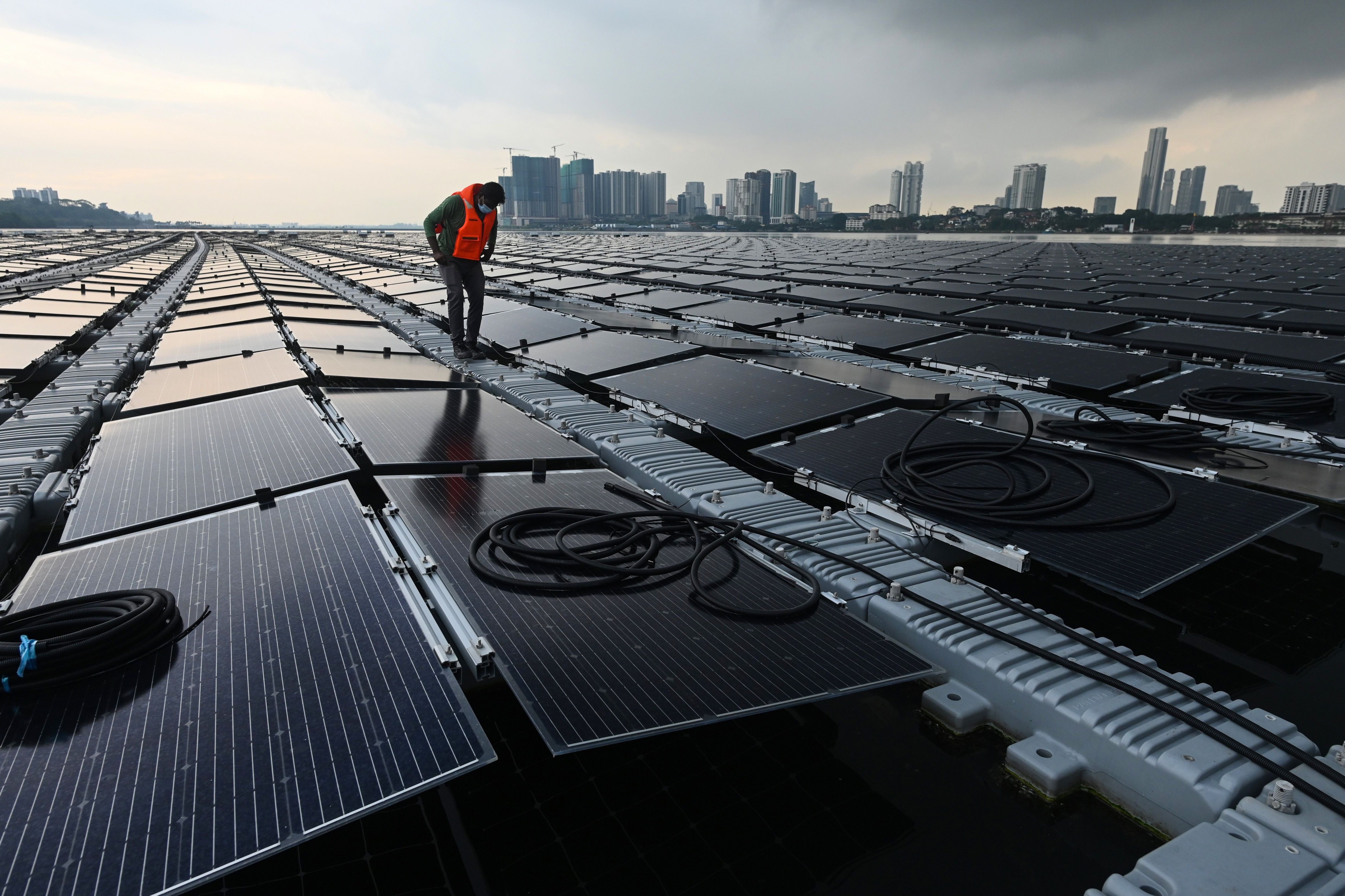 A worker checks cables on a floating solar power farm at sea off Singapore’s northern coast