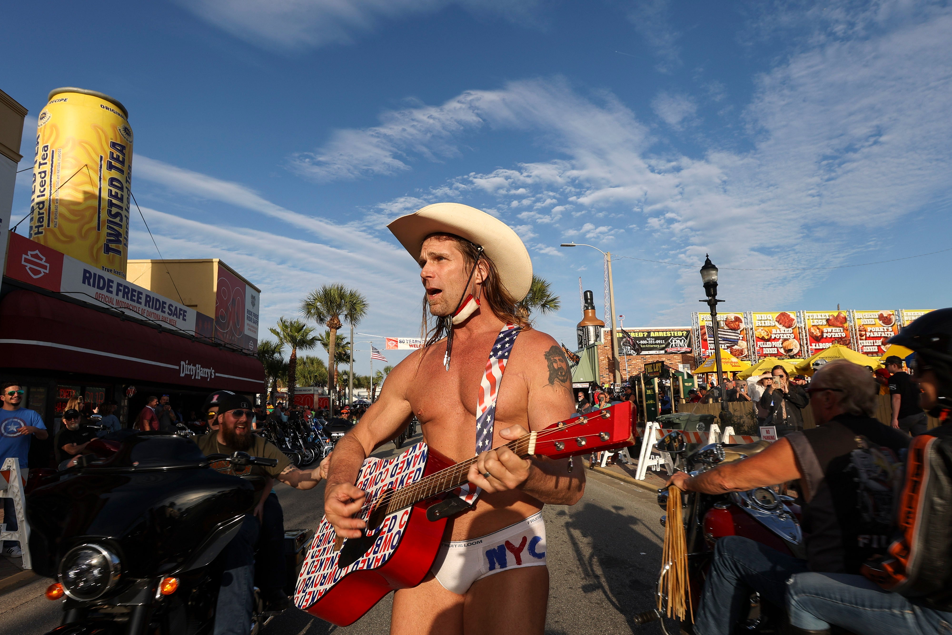 Robert Burck, better known as the Naked Cowboy, walks down the middle of Main Street while performing in Daytona, Fla., during the start of Bike Week on Friday, March 5, 2021. Police arrested the Times Square performer on a misdemeanor resisting arrest charge and cited him for panhandling as he worked a gig at Bike Week. (Sam Thomas/Orlando Sentinel via AP)