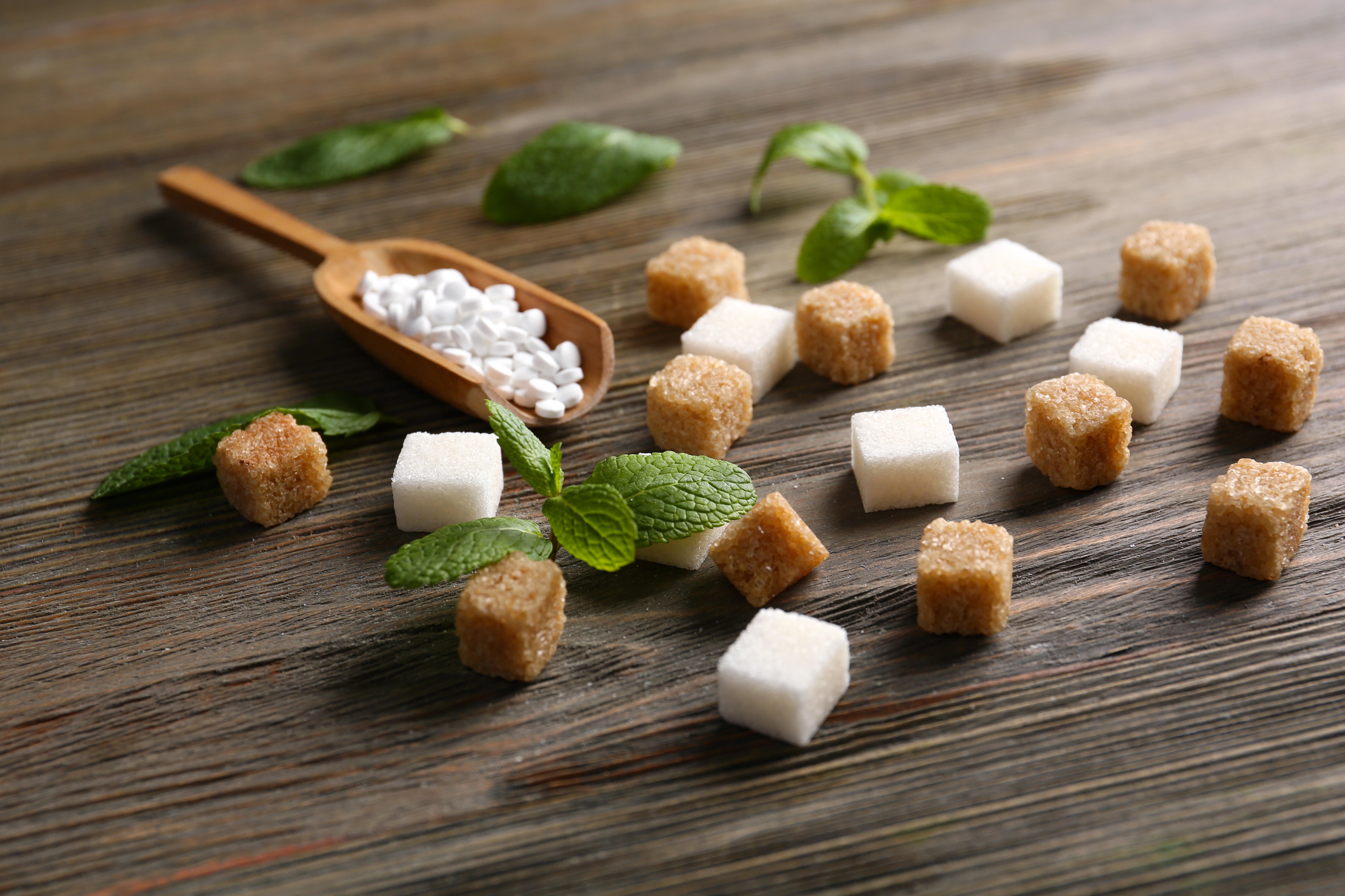 Sugar cubes and stevia on wooden background