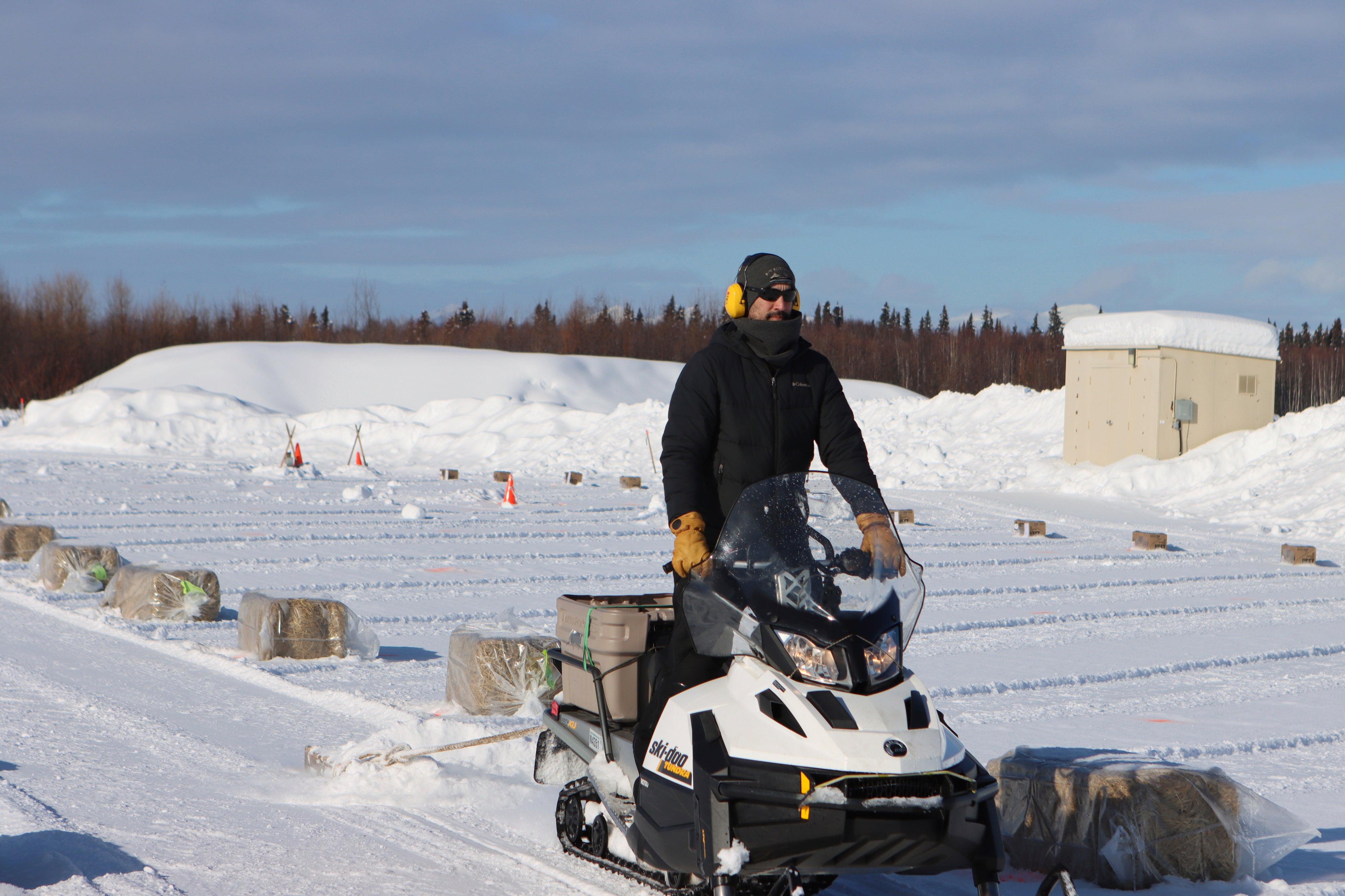 A snow machiner drags a pallet to smooth out snow lanes in the new dog lot which has been set up at the McGrath checkpoint to accommodate COVID-19 precautions during the Iditarod Sled Dog Race on Tuesday March 9, 2021, in Alaska