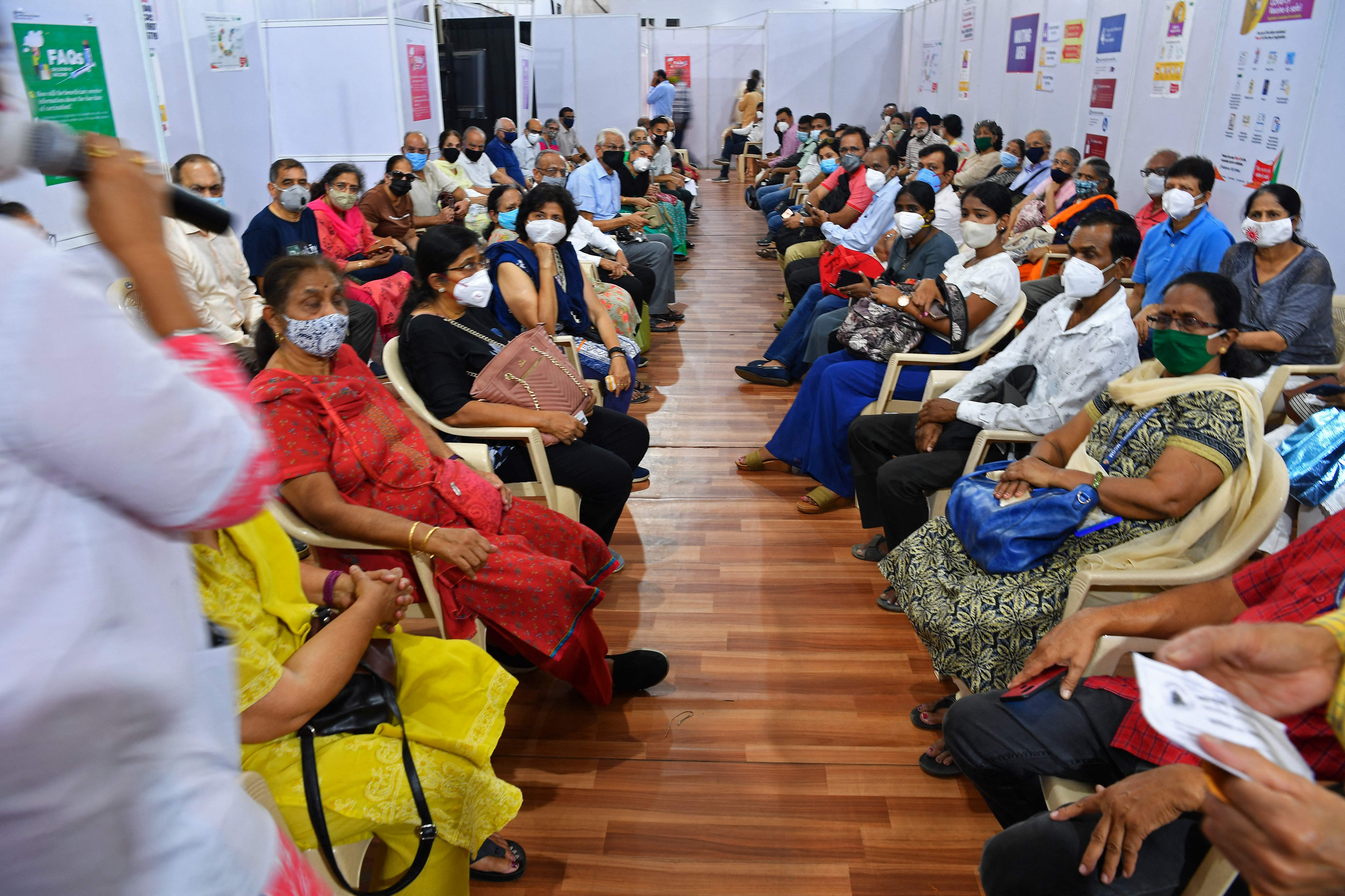 People listen to a medical staff as they wait to receive the Covid-19 coronavirus vaccine at a vaccination centre in Mumbai on 4 March , 2021